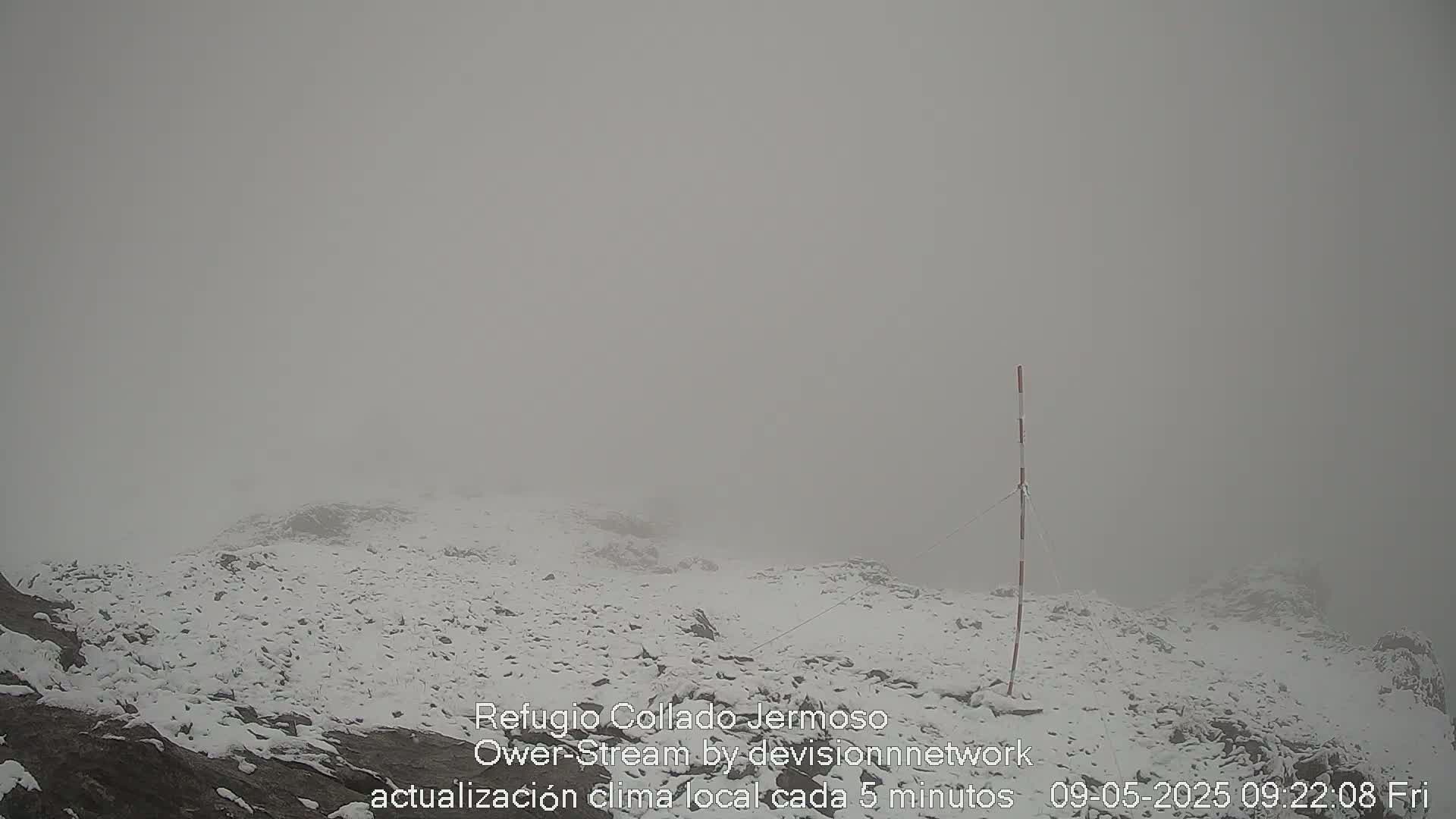 A snow-covered, rocky landscape is shrouded in thick fog.