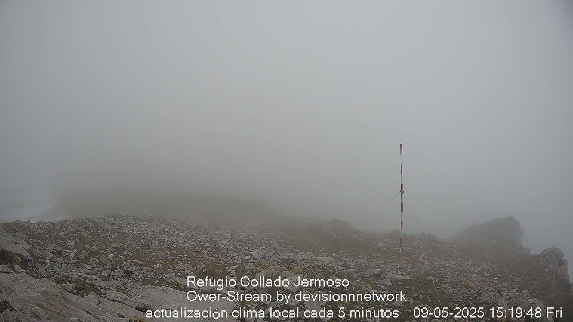 A rocky, fog-shrouded landscape features a tall, marked pole.