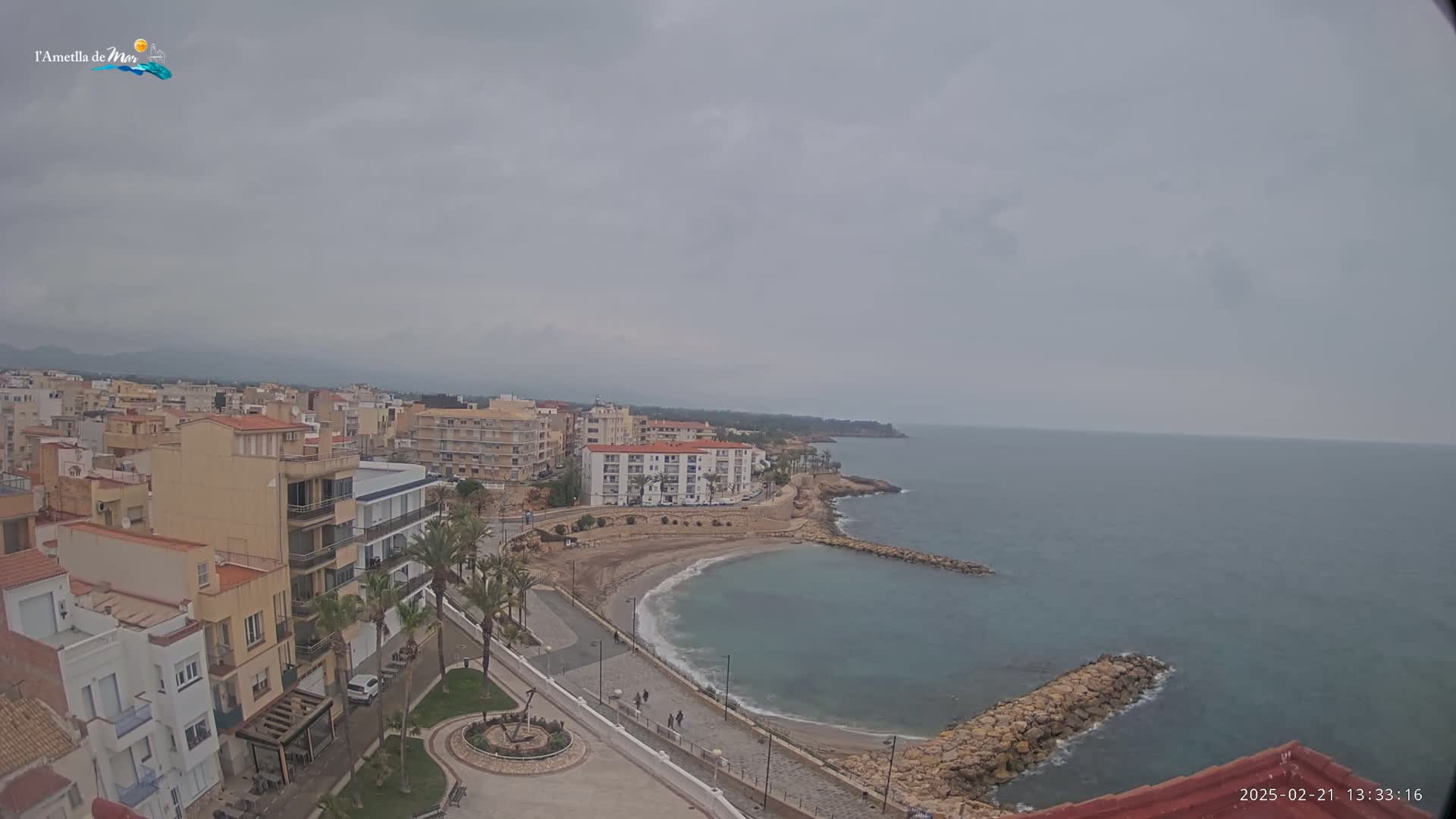 A coastal town with buildings and a small beach is seen on an overcast day.