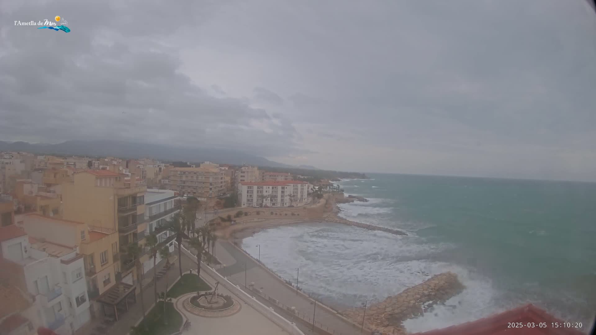 A coastal town under an overcast sky with waves crashing against a rocky shore.