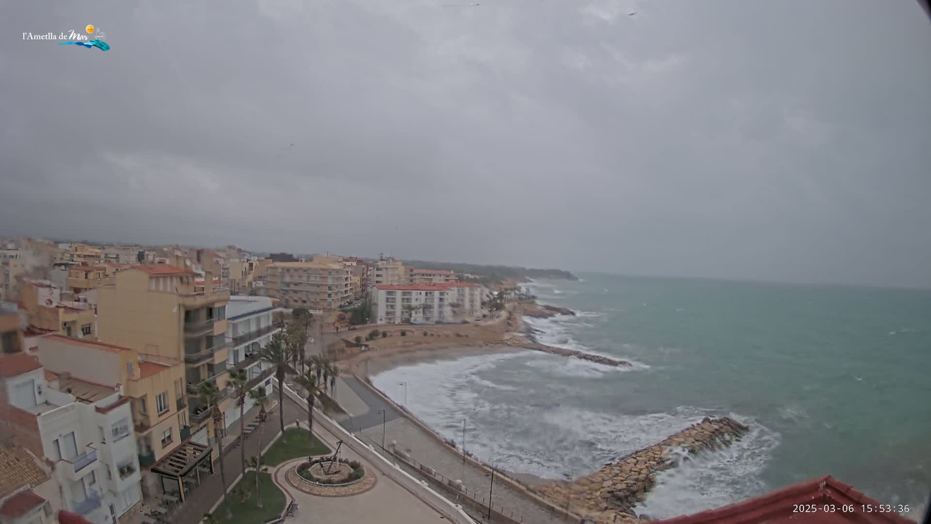 A coastal town under an overcast sky with choppy waves crashing against a rocky shore.