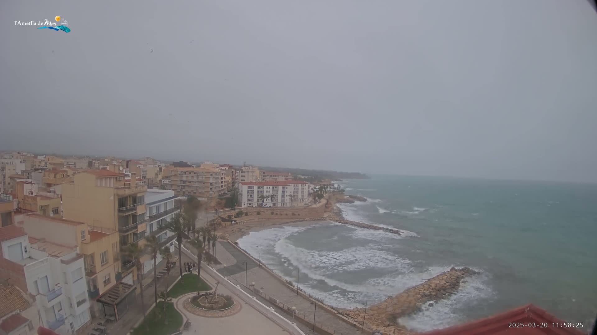 A coastal town is shown on an overcast day with choppy waves crashing against a rocky shoreline.