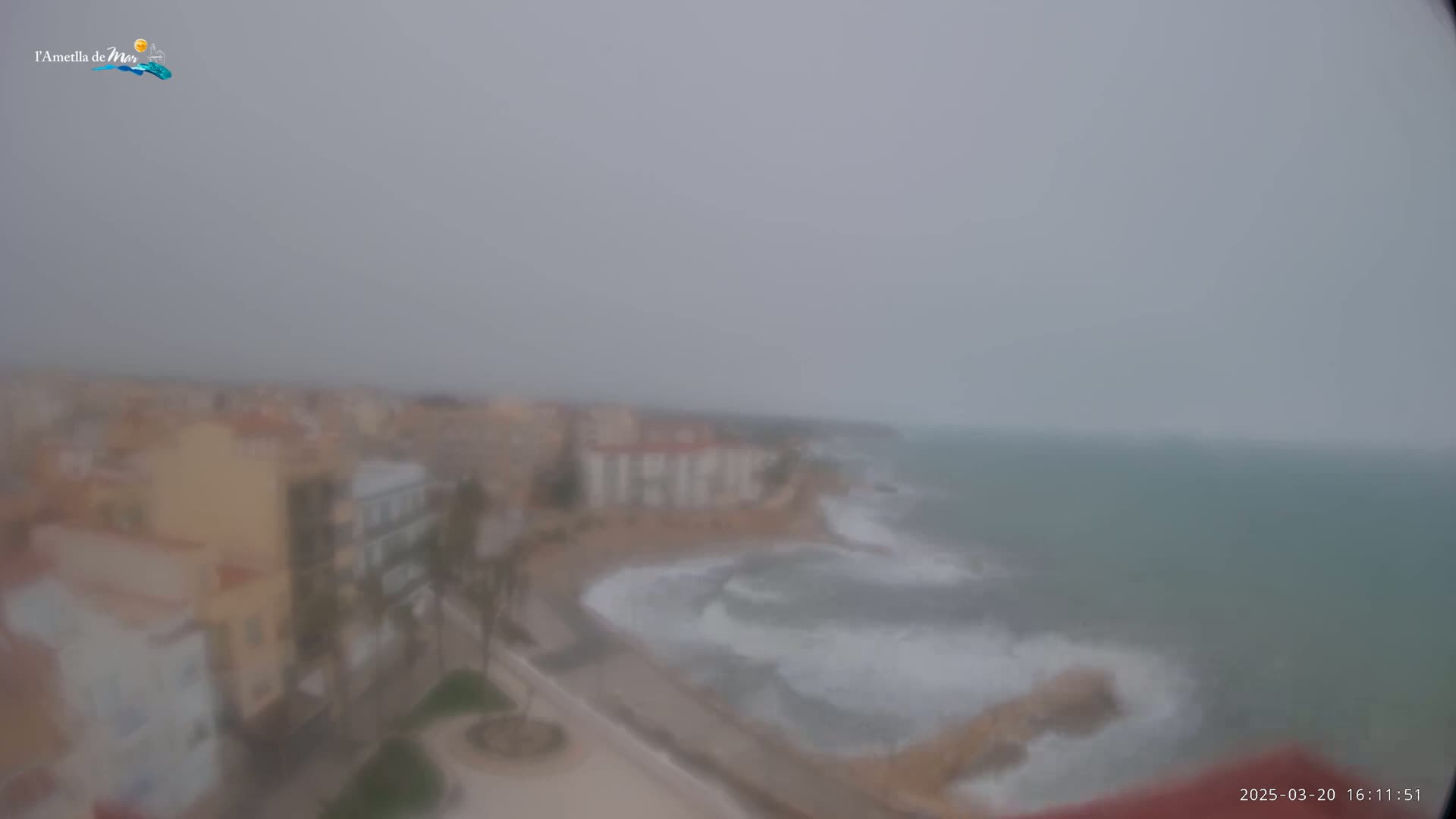 A hazy coastal town is seen from above, with a rough sea visible in the distance under an overcast sky.