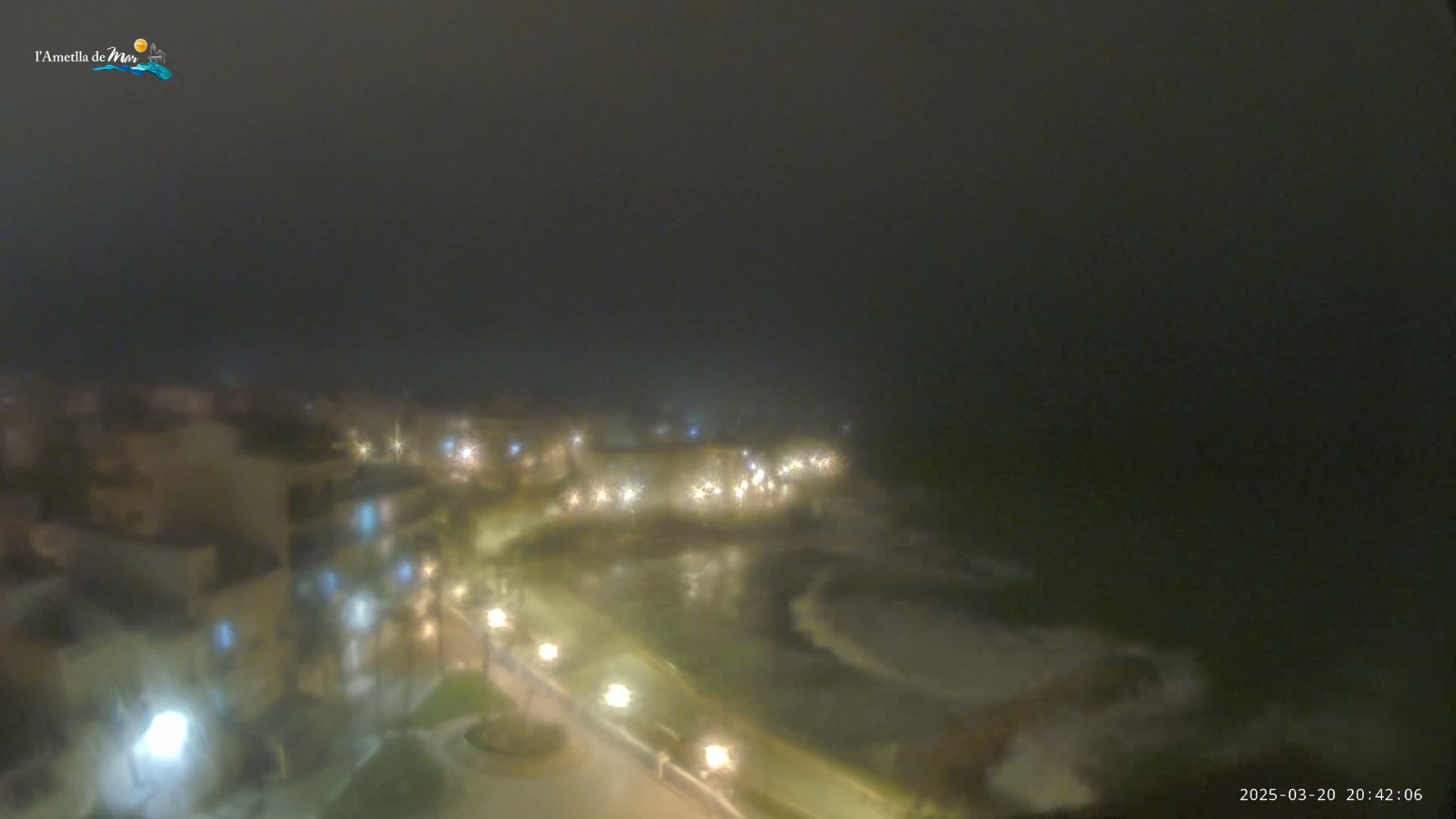 A foggy night scene shows a town with illuminated buildings and streets.