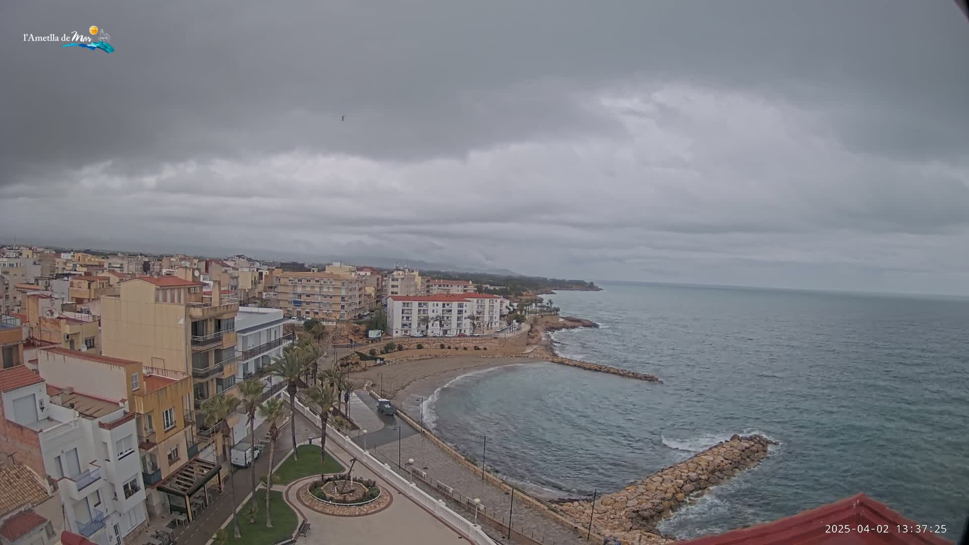 An elevated view shows a coastal town under an overcast sky, with a small, sandy cove and calm ocean visible in the foreground.
