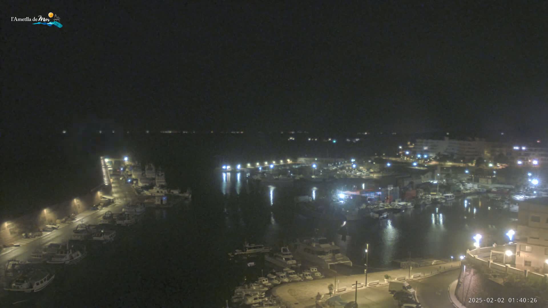 A nighttime, high-angle view of a harbor filled with numerous boats and surrounded by buildings and streetlights.