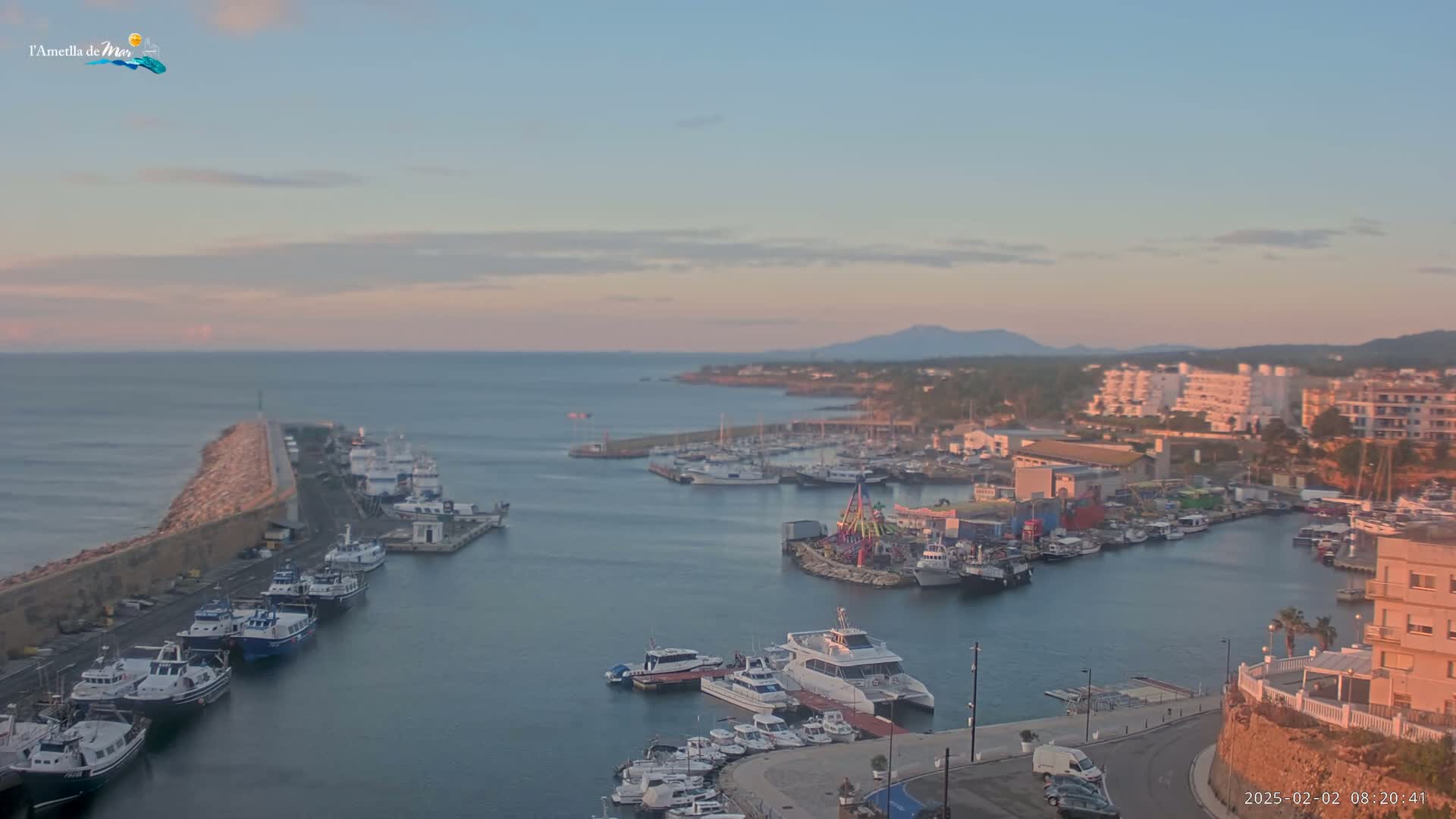 A calm harbor filled with numerous boats at sunset, under a clear, pale sky.