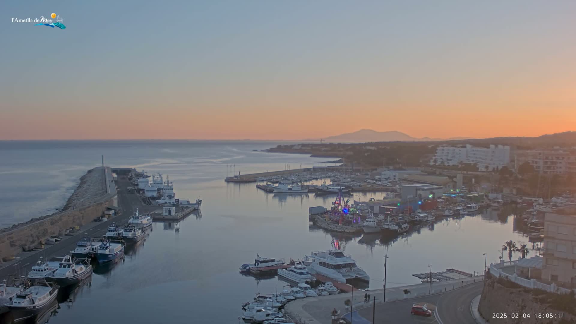 A harbor filled with numerous boats is seen at sunset, under a clear sky.
