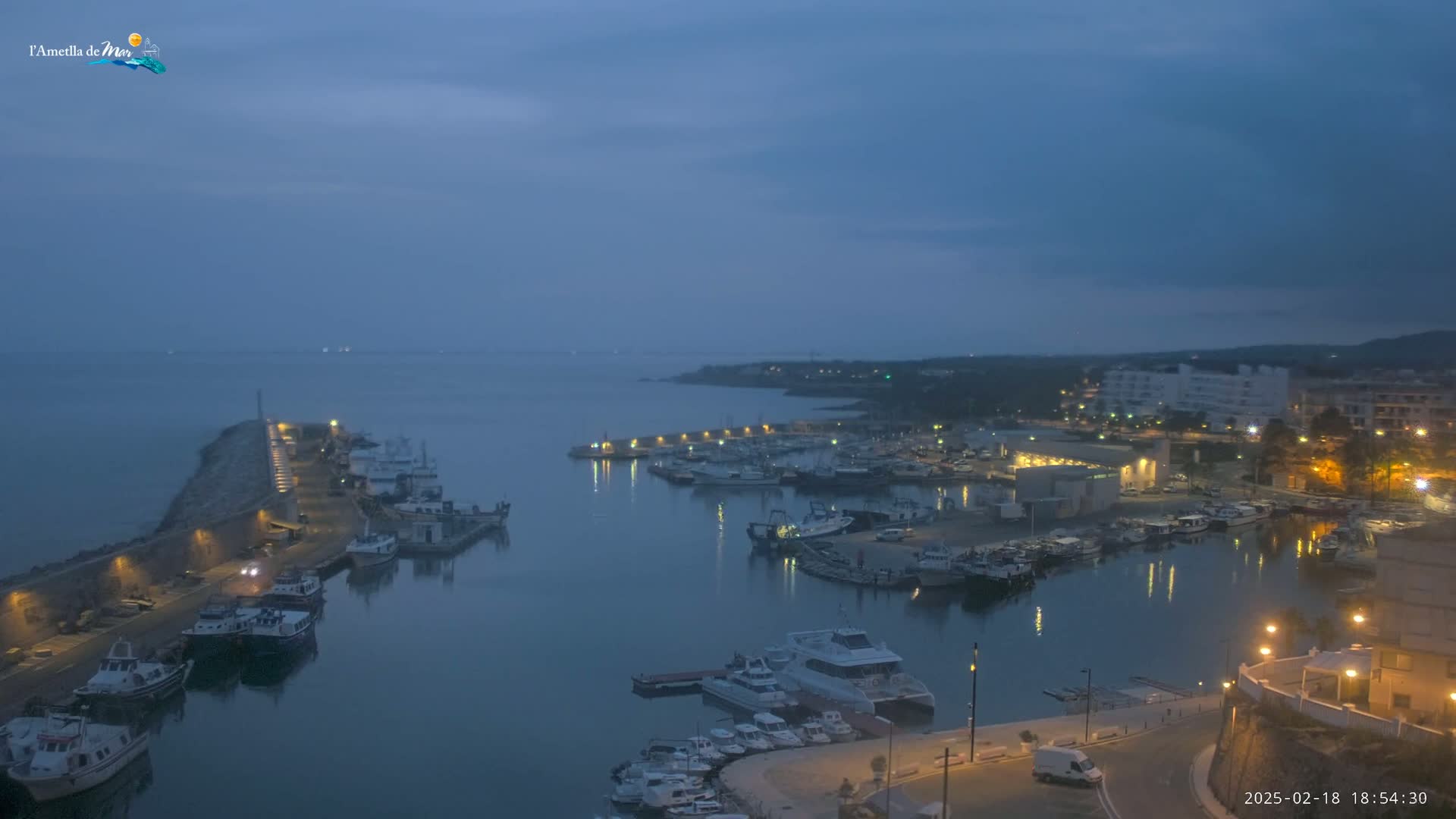 A harbor filled with boats is illuminated at twilight under a dusky sky.