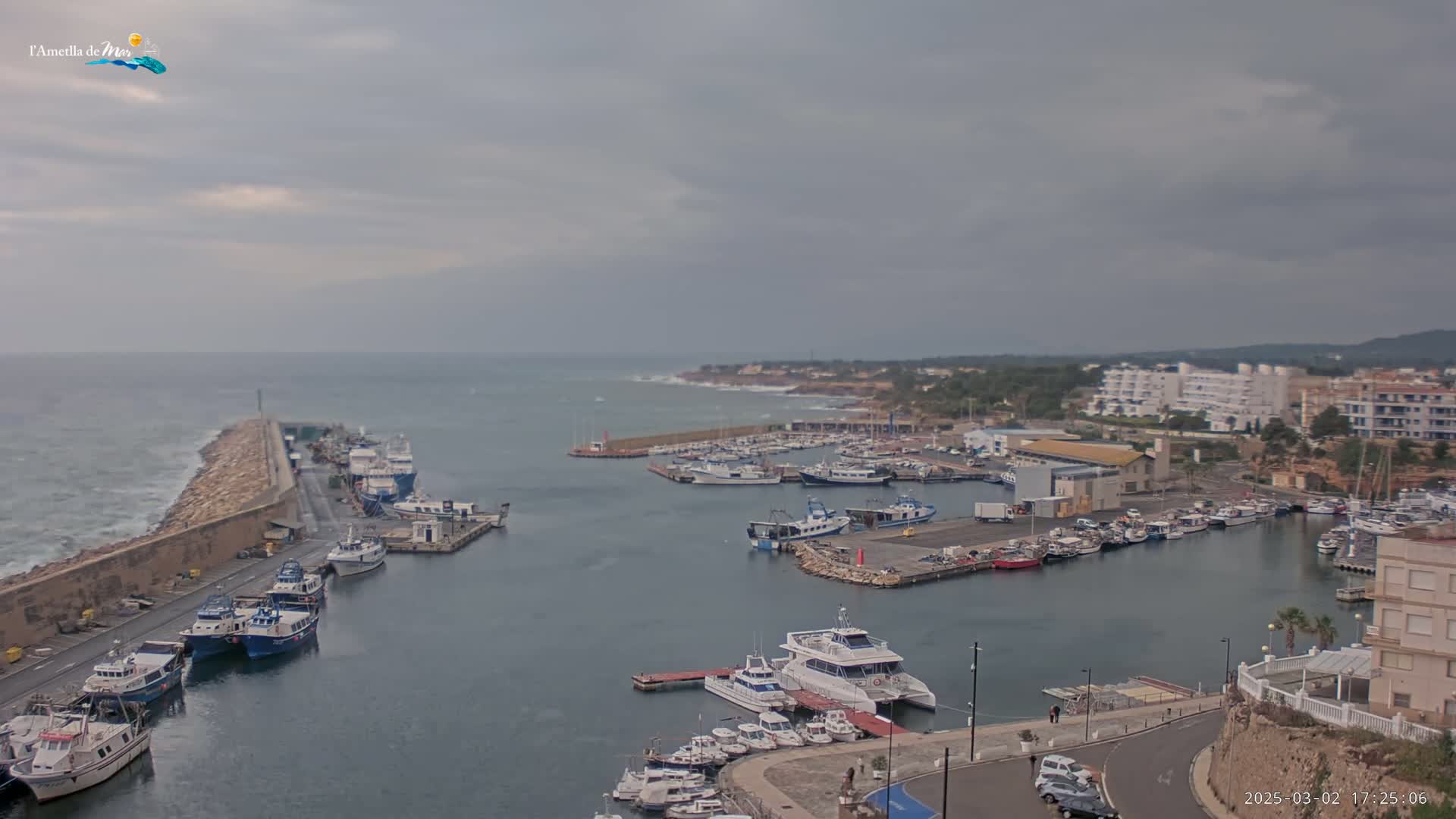 A harbor filled with numerous boats and yachts is seen under an overcast sky.