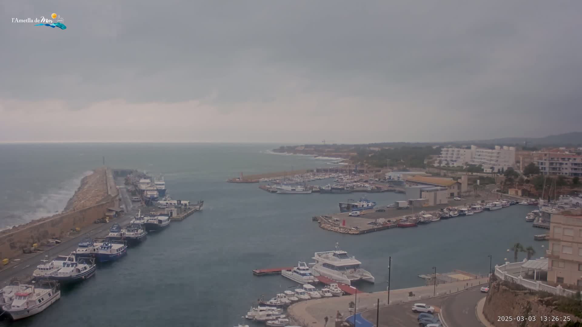 A harbor filled with numerous boats is shown under an overcast sky with choppy water visible beyond a breakwater.