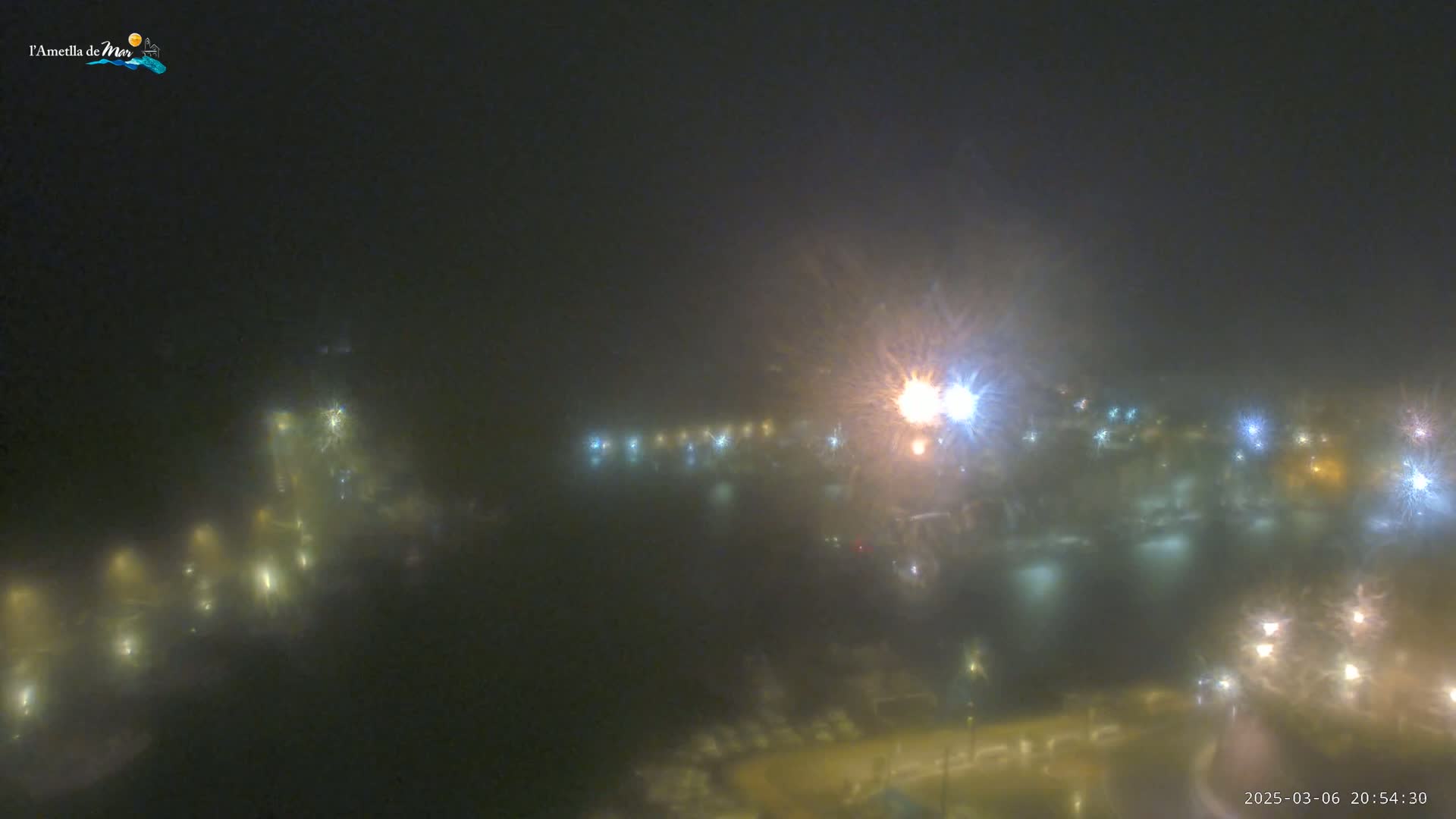 A foggy night scene shows distant lights from a town or city, appearing blurred and hazy.