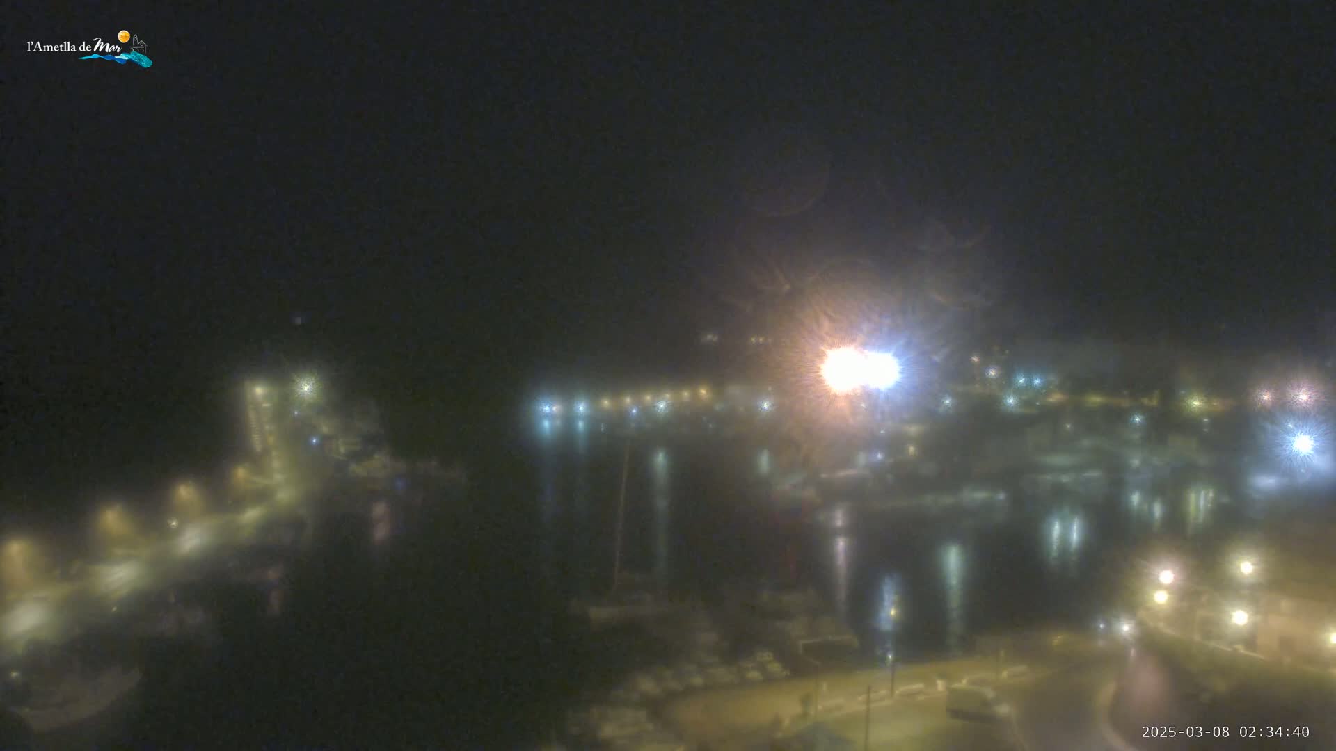 A nighttime, foggy view of a harbor with lights illuminating boats and the surrounding area.