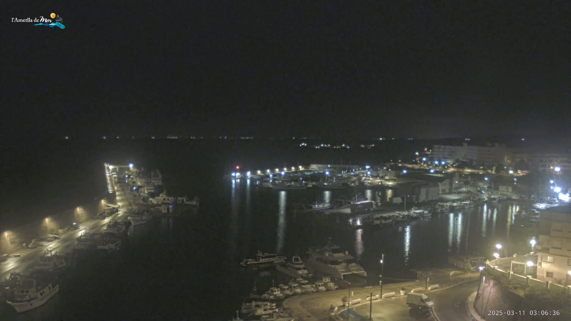 A nighttime, high-angle view of a harbor filled with boats, illuminated by lights along the docks and buildings.