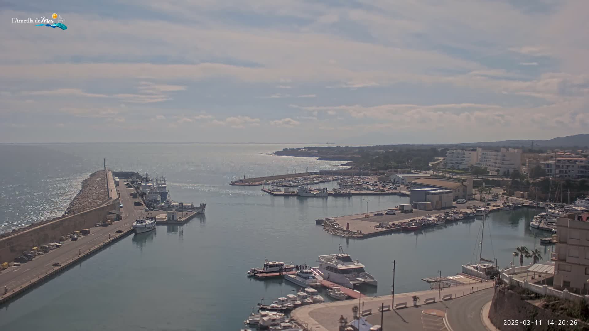 A harbor filled with boats and surrounded by buildings, under a partly cloudy sky.