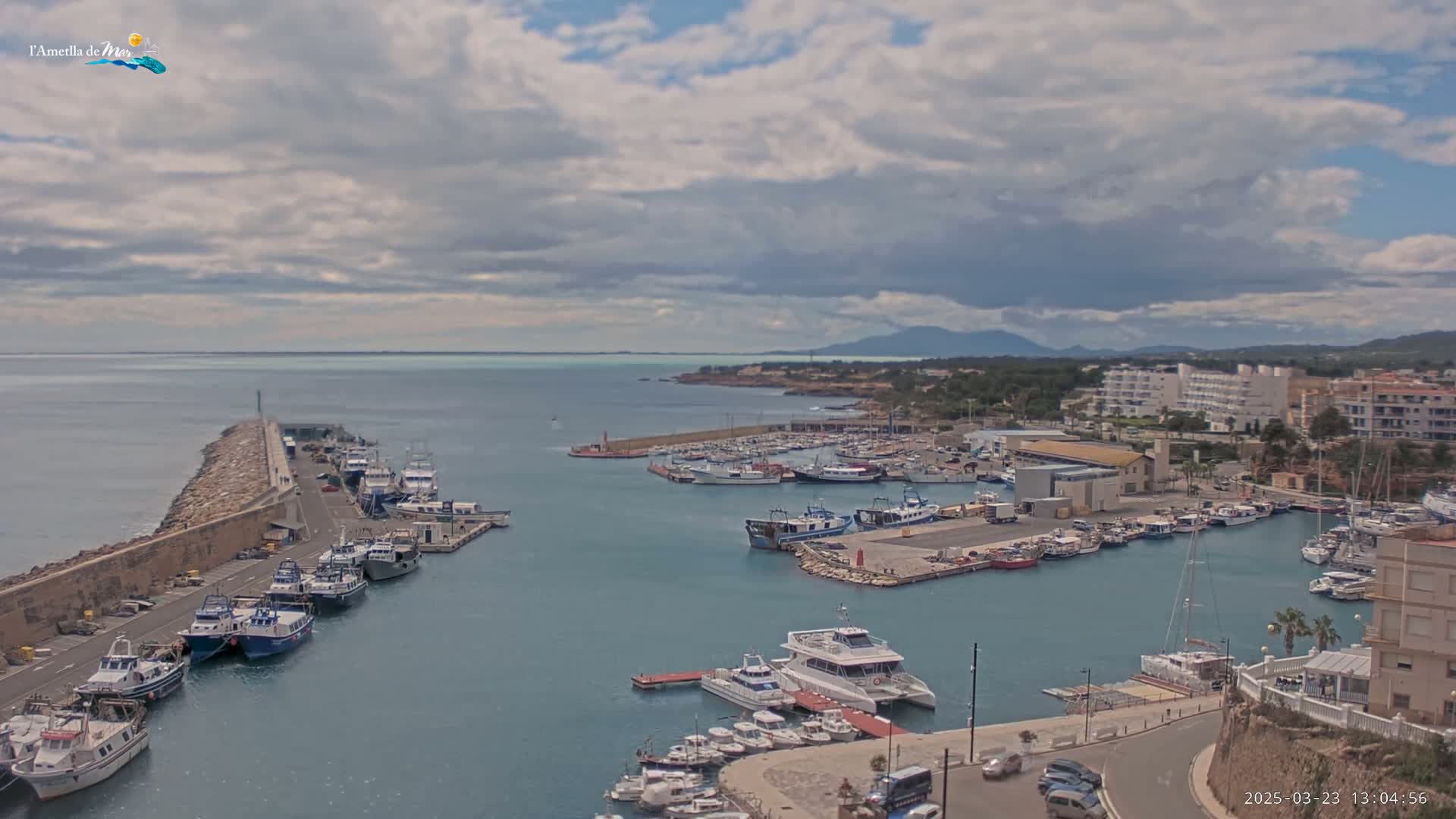 A harbor filled with numerous boats and yachts under a partly cloudy sky.
