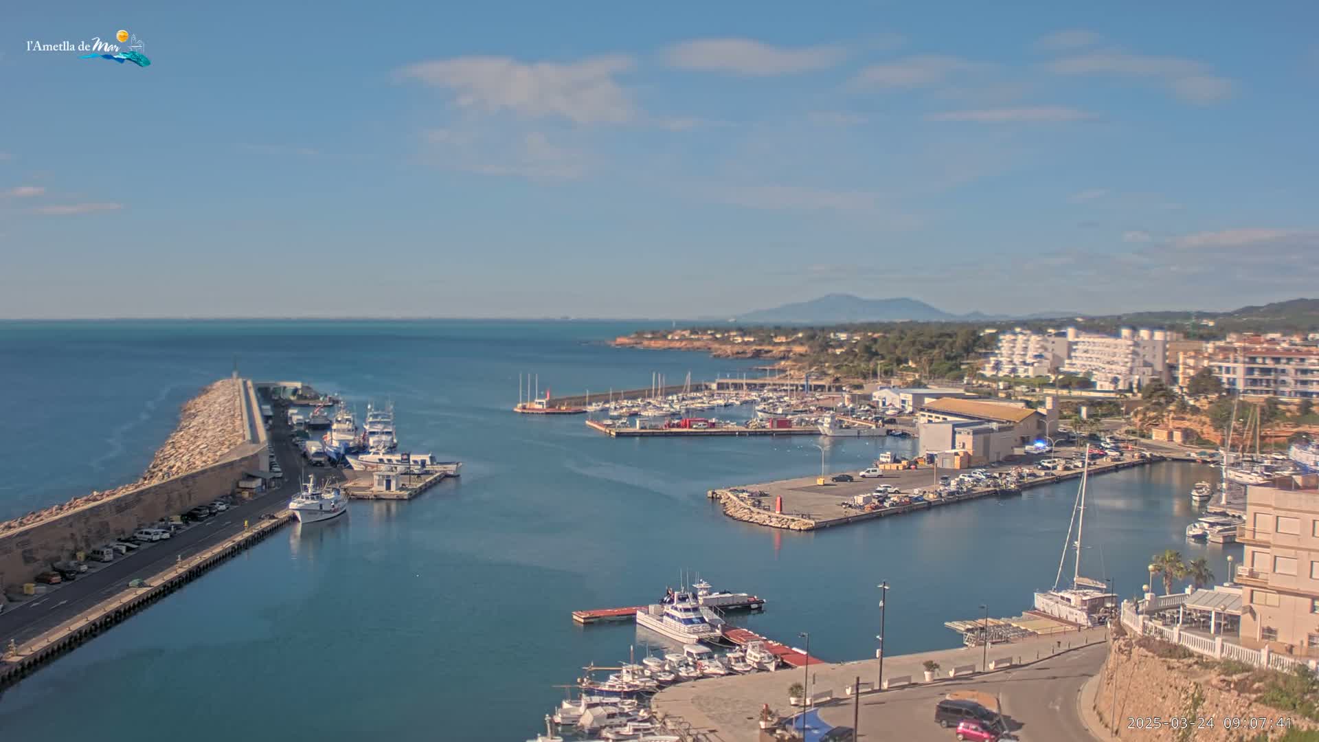 A harbor filled with numerous boats and surrounded by buildings, under a mostly clear sky.