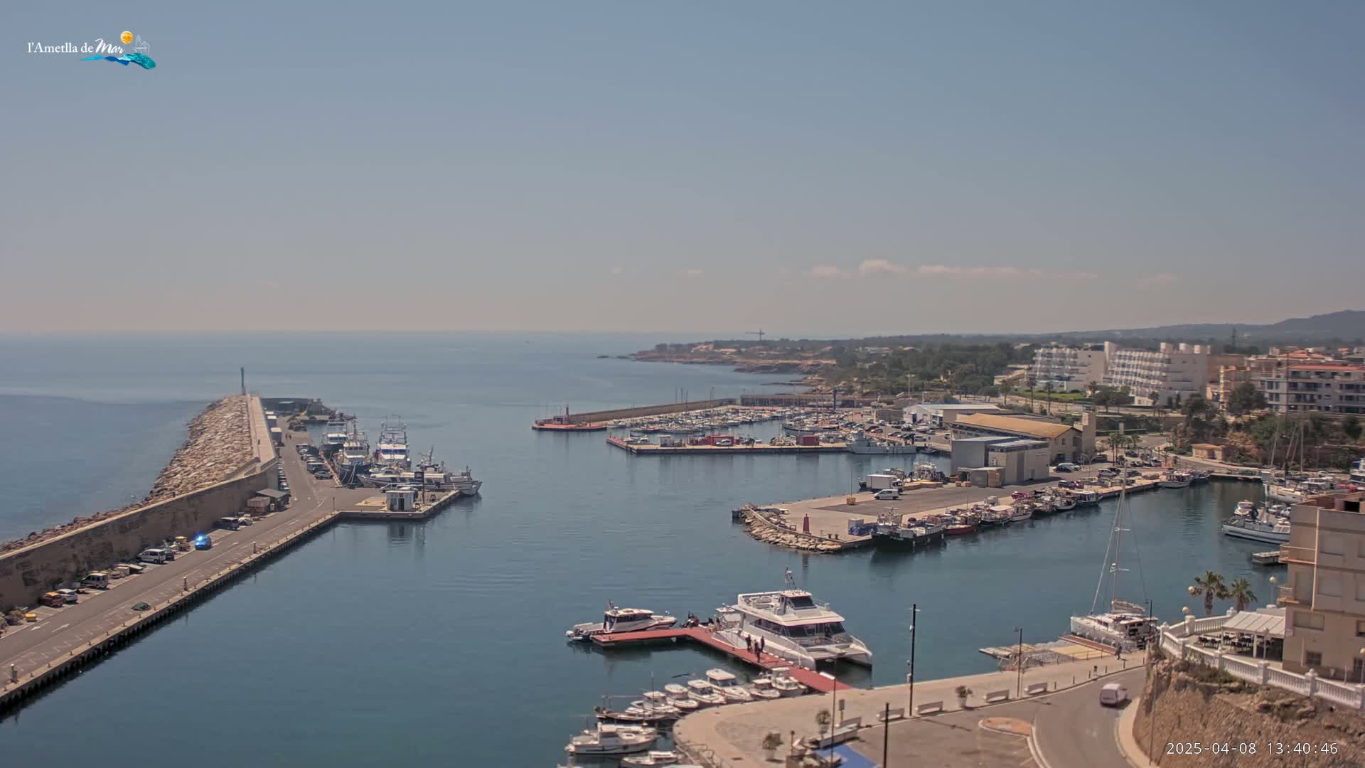 A harbor filled with numerous boats and yachts is situated next to a coastline on a sunny day.