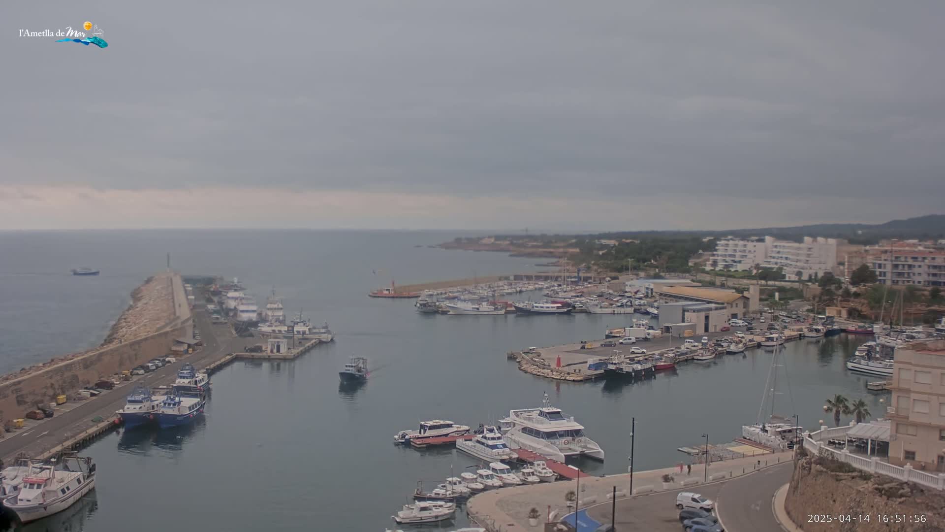 A harbor filled with numerous boats and yachts is shown under an overcast sky.