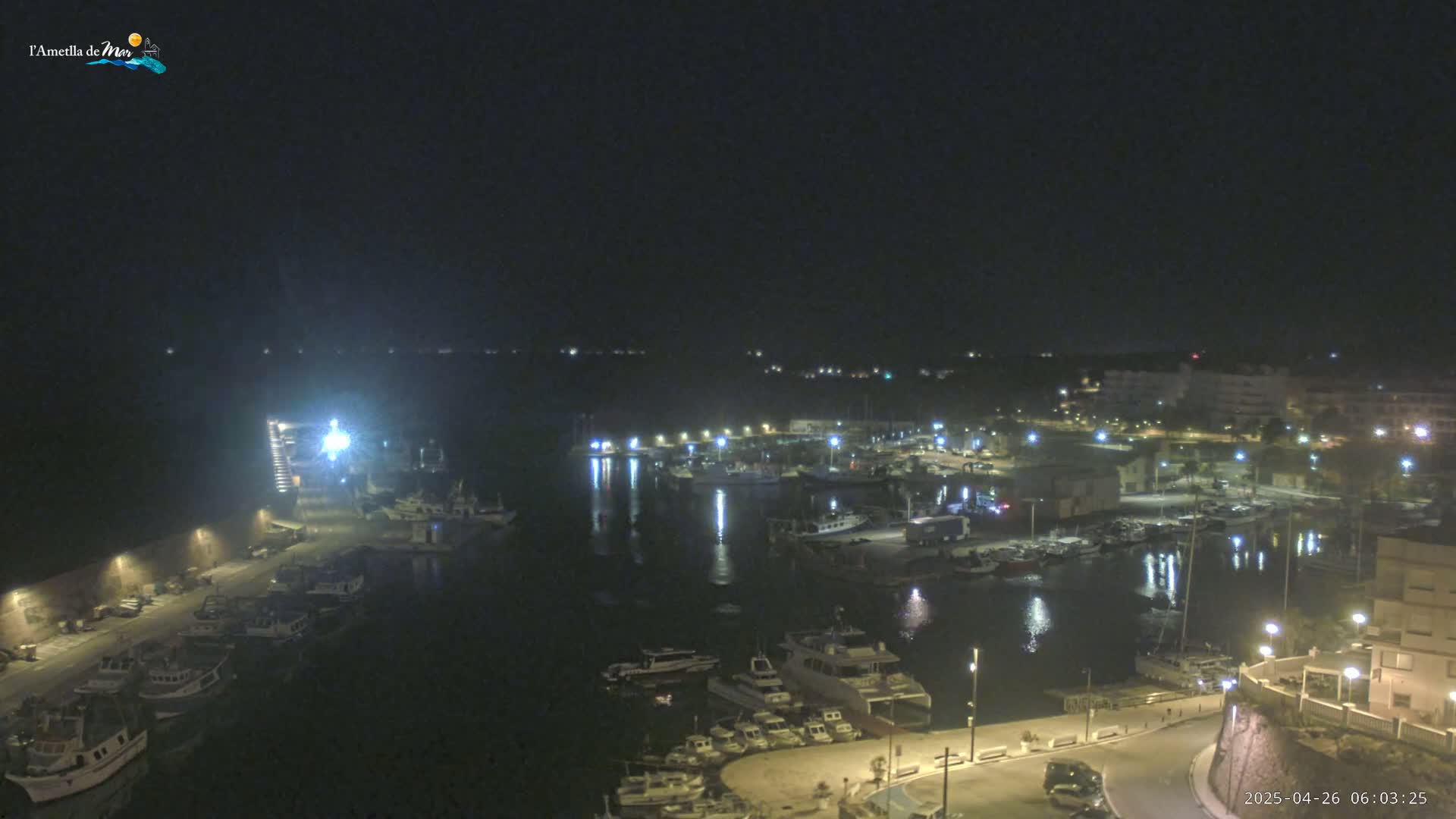 A nighttime, high-angle view of a harbor filled with boats, illuminated by lights along the docks and buildings in the surrounding area.