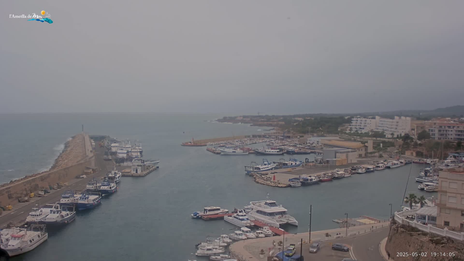 A harbor filled with numerous boats and ships is shown under an overcast sky.
