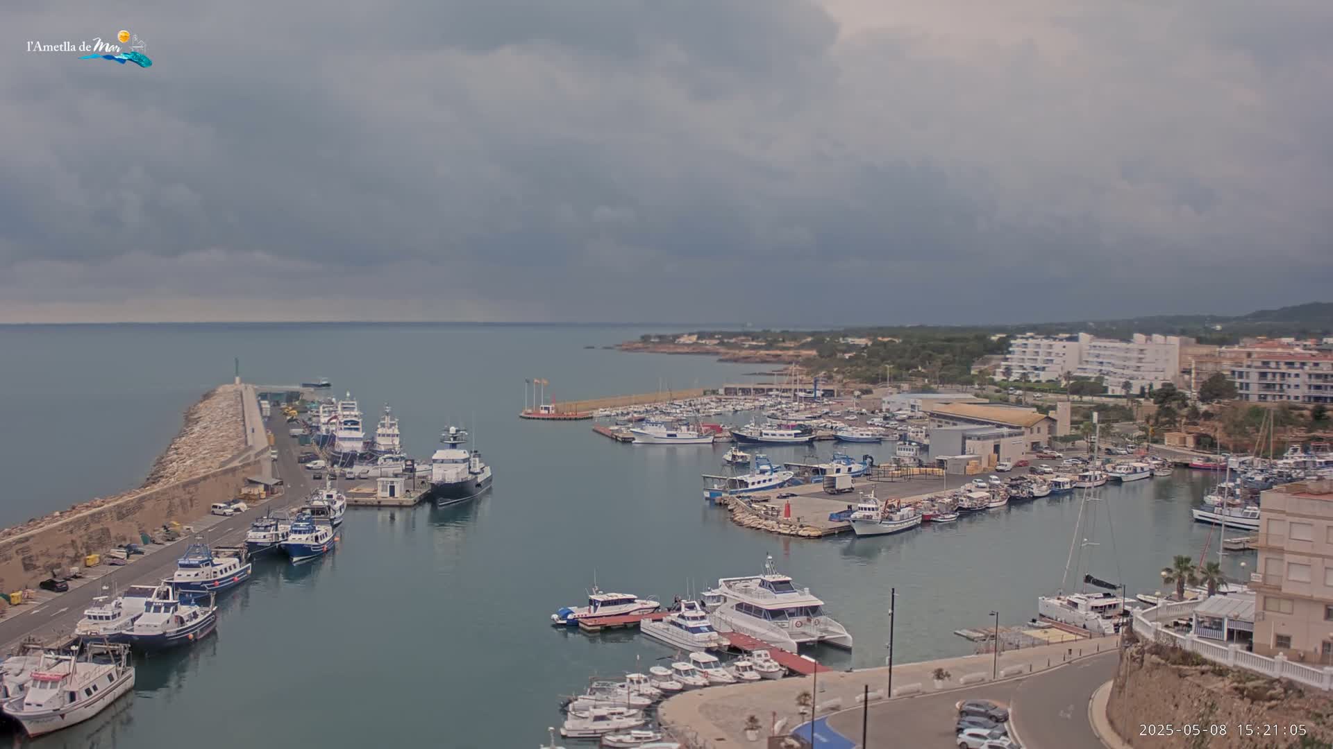 A harbor filled with numerous boats and yachts is seen under a cloudy sky.