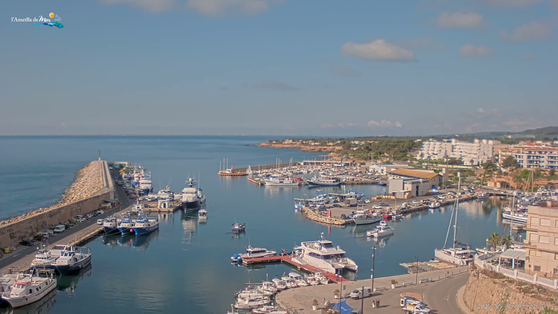 A harbor filled with numerous boats and yachts under a mostly clear, sunny sky.