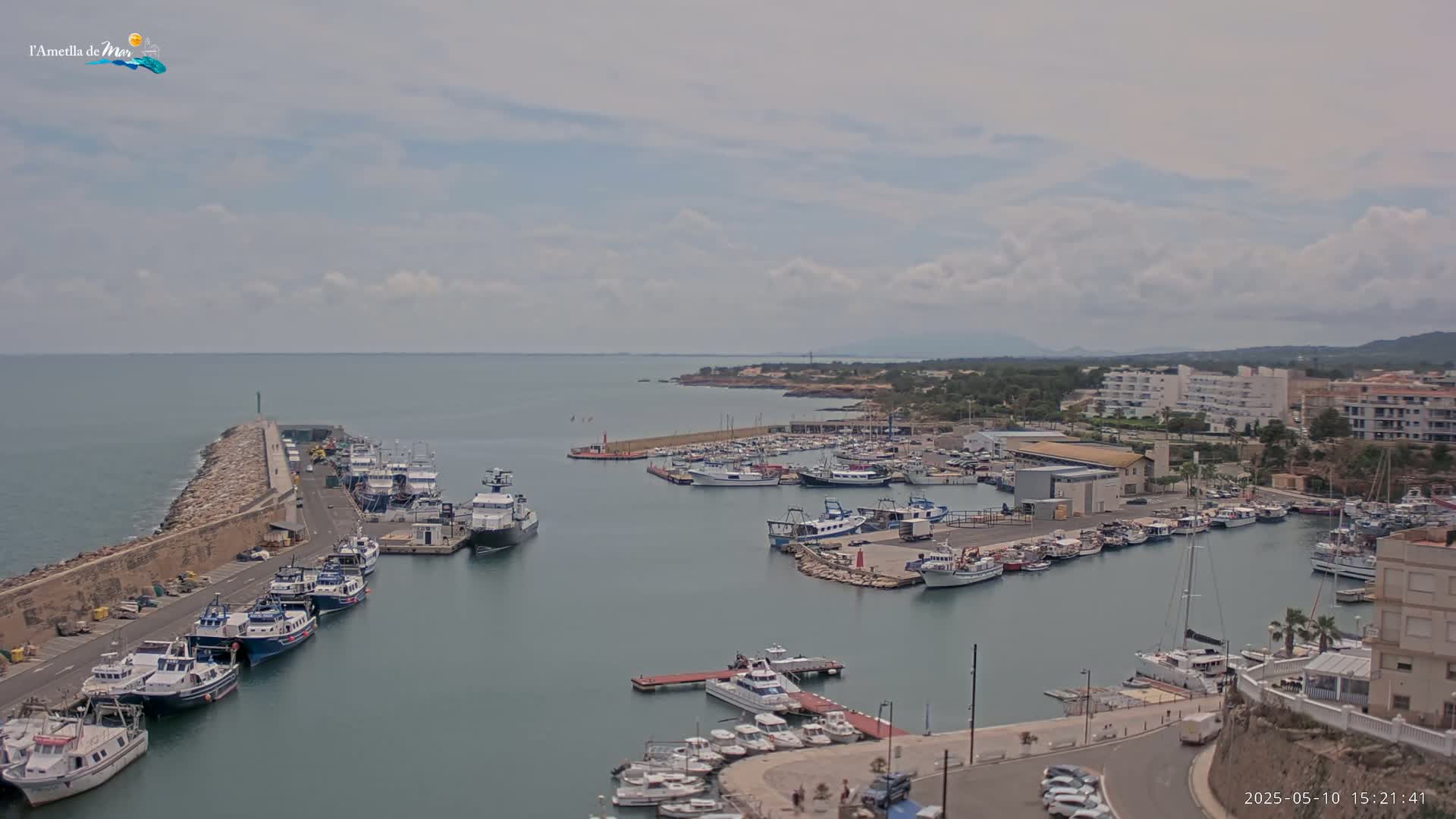 A harbor filled with numerous boats and yachts is seen under a partly cloudy sky.