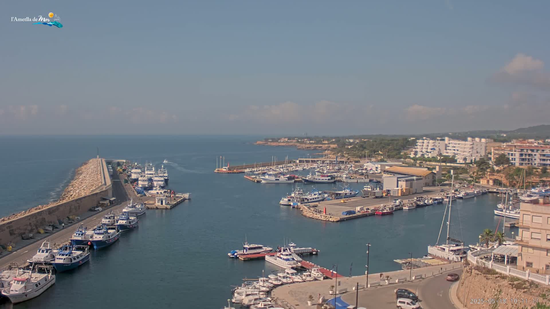 A harbor filled with numerous boats and yachts is situated beside a coastline under a mostly clear sky.