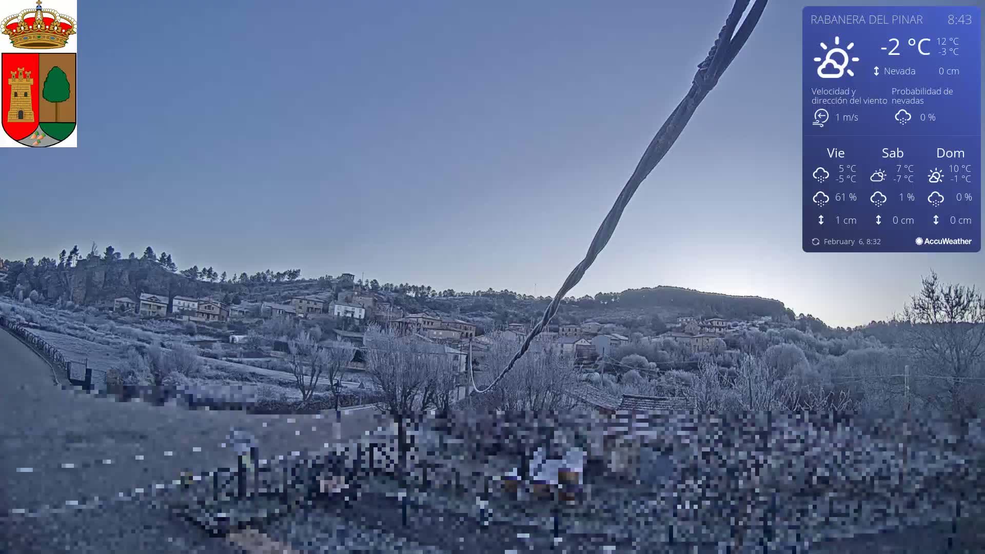A snow-covered village is nestled on a hillside under a clear, twilight sky.