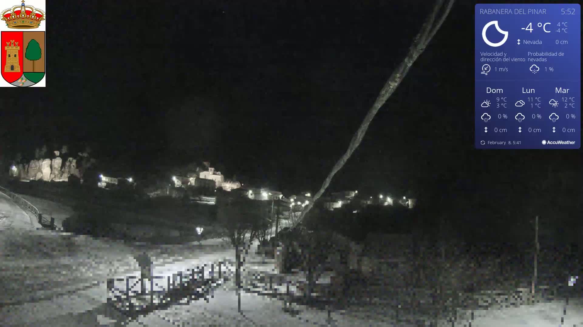A snow-covered village is illuminated at night under a clear, dark sky.