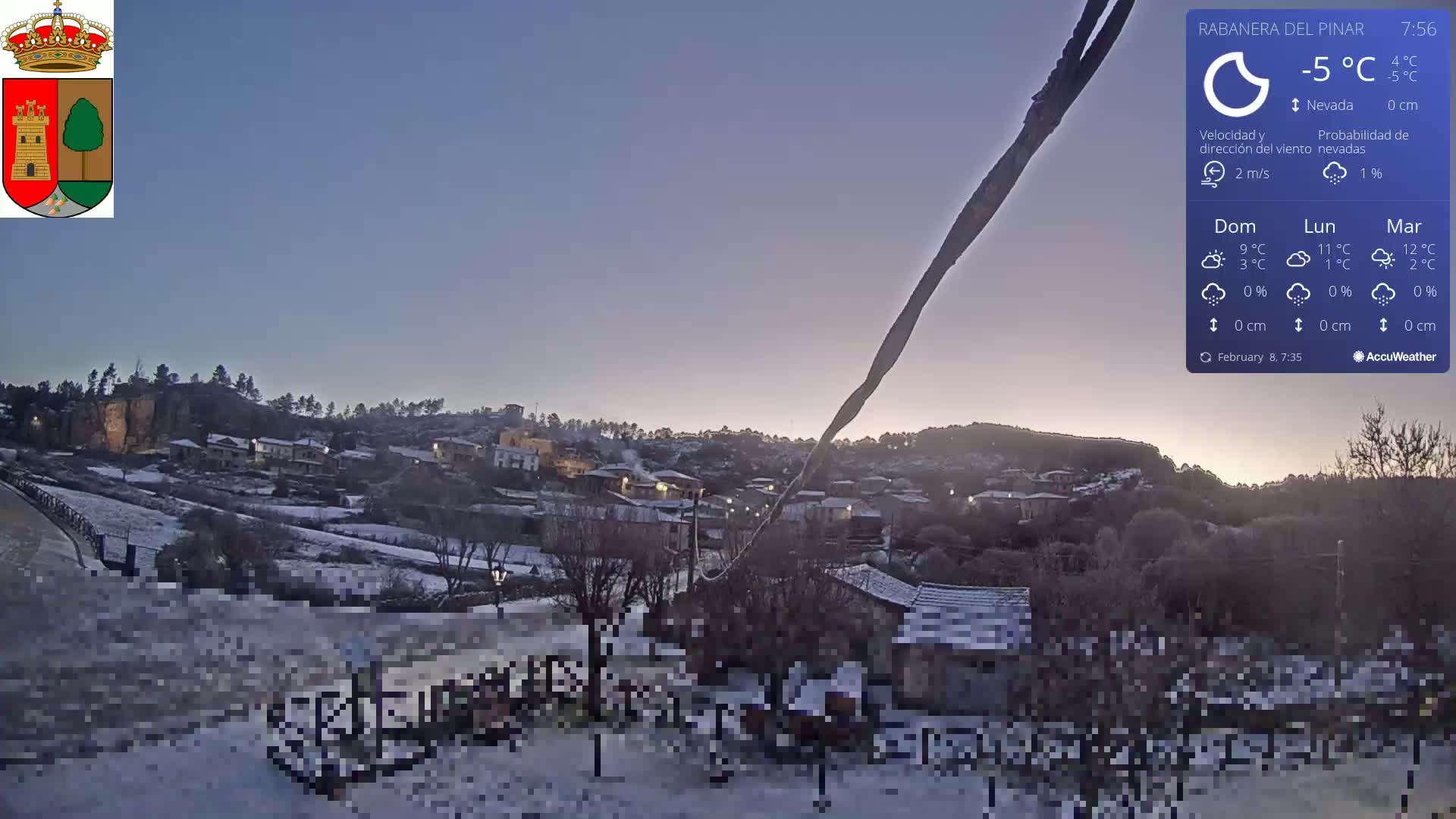 A snow-covered village is nestled on a hillside under a twilight sky.