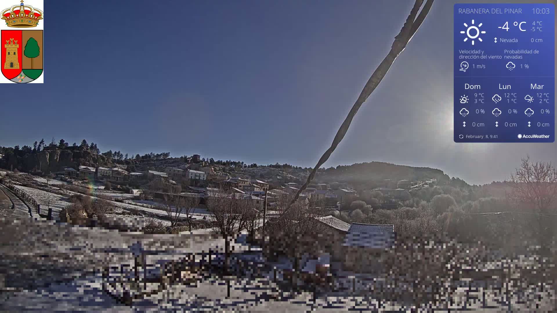 A snow-covered village sits on a hillside under a clear blue sky.