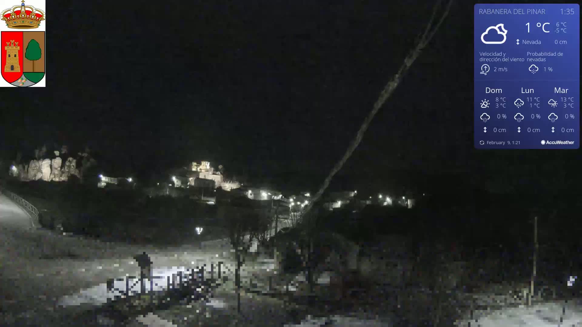 A nighttime view of a snow-covered village under a cloudy sky.