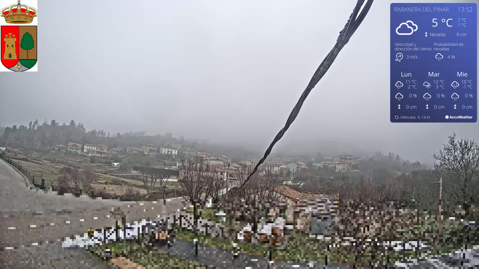 A foggy view of a small town nestled in a hillside, with a wire stretching across the foreground.