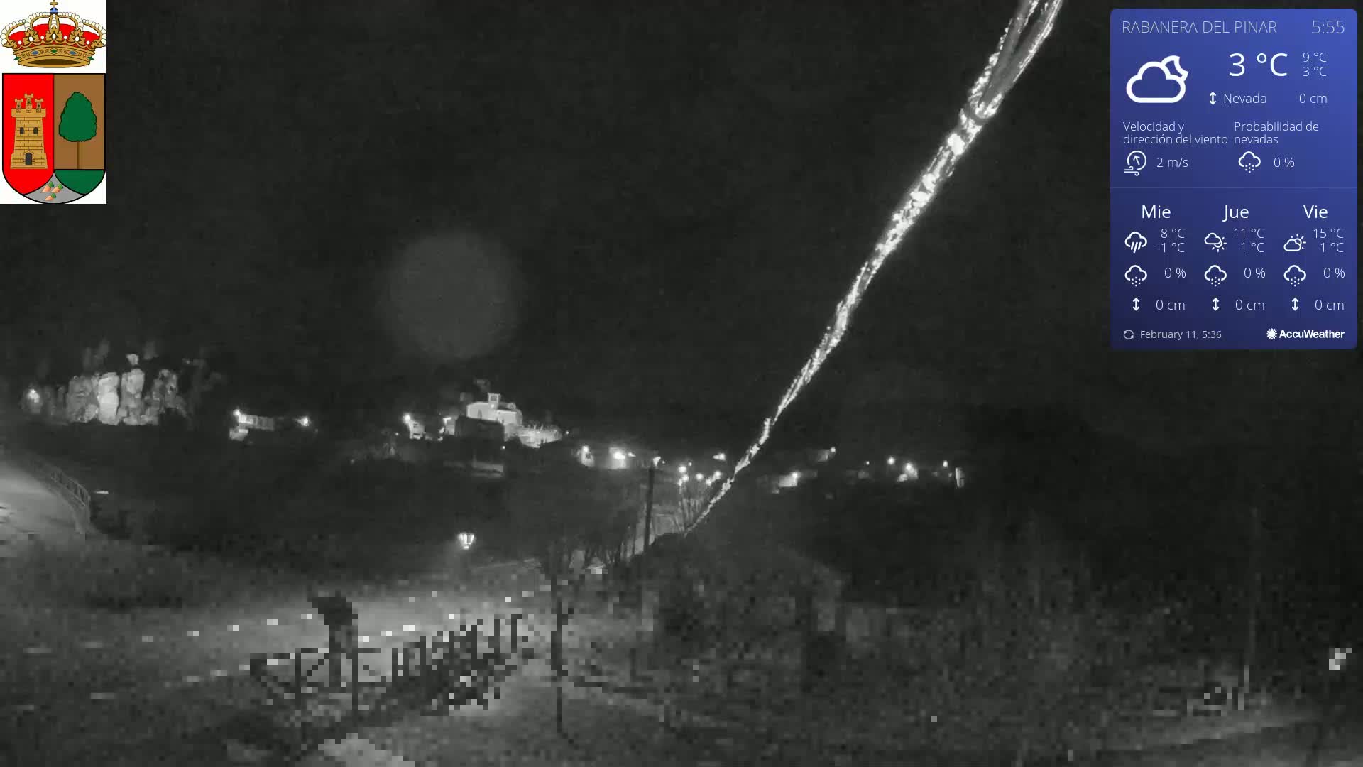 A nighttime view of a dimly lit town under a mostly clear sky, with a 3°C temperature and a light breeze.