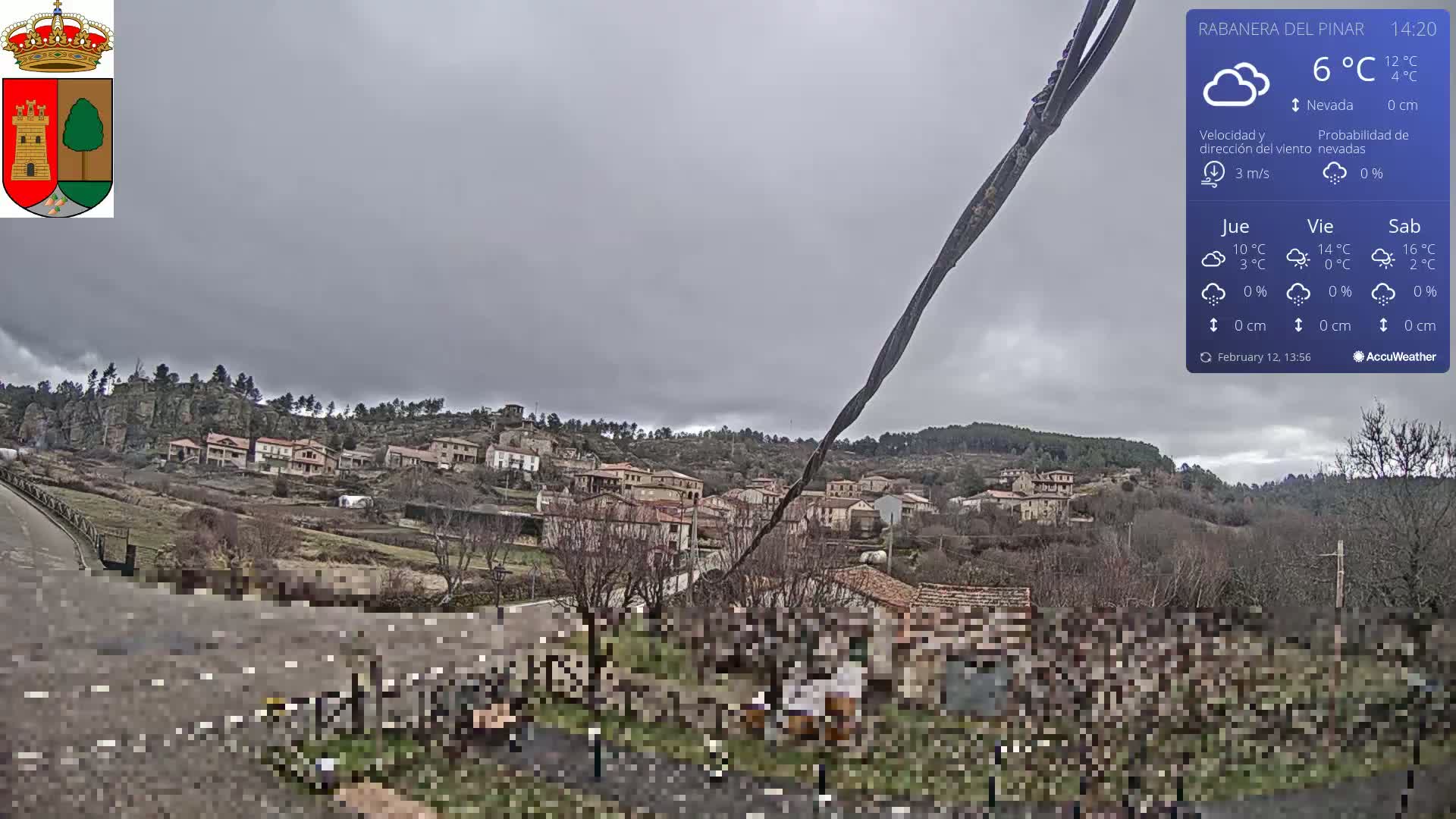 A small village nestled on a hillside under an overcast sky is viewed from a slightly elevated position.