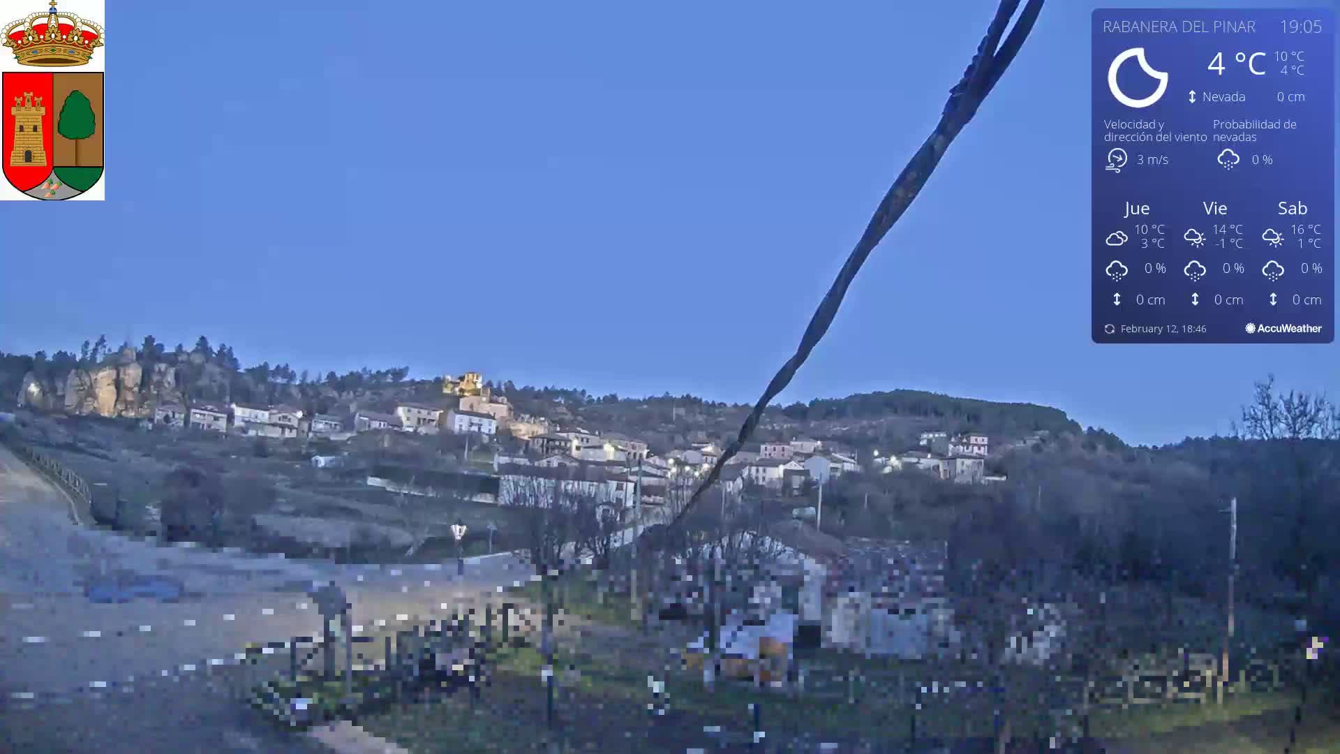 A small town nestled in a hillside is visible under a twilight sky; the weather is clear and 4°C.
