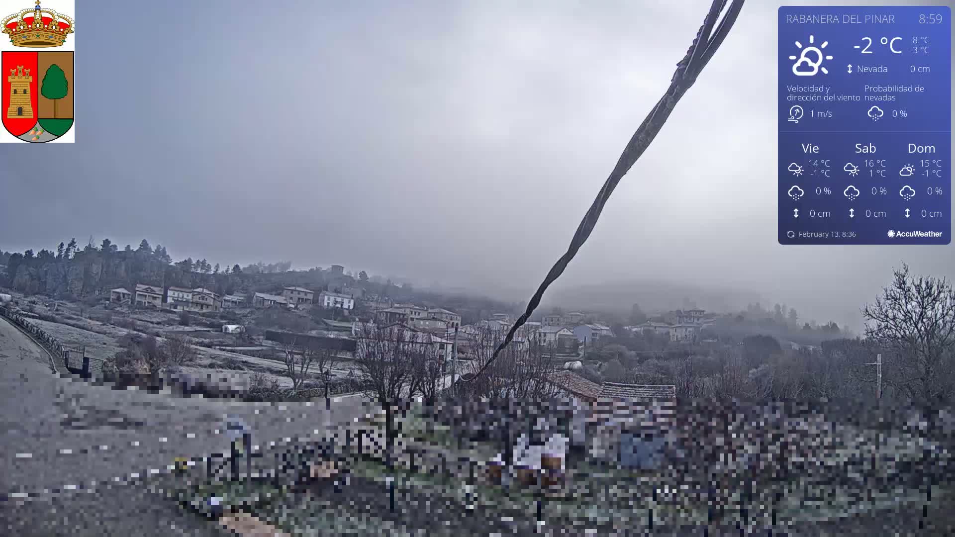 A hazy, foggy view of a small town nestled in a valley, with a few people gathered in the foreground.