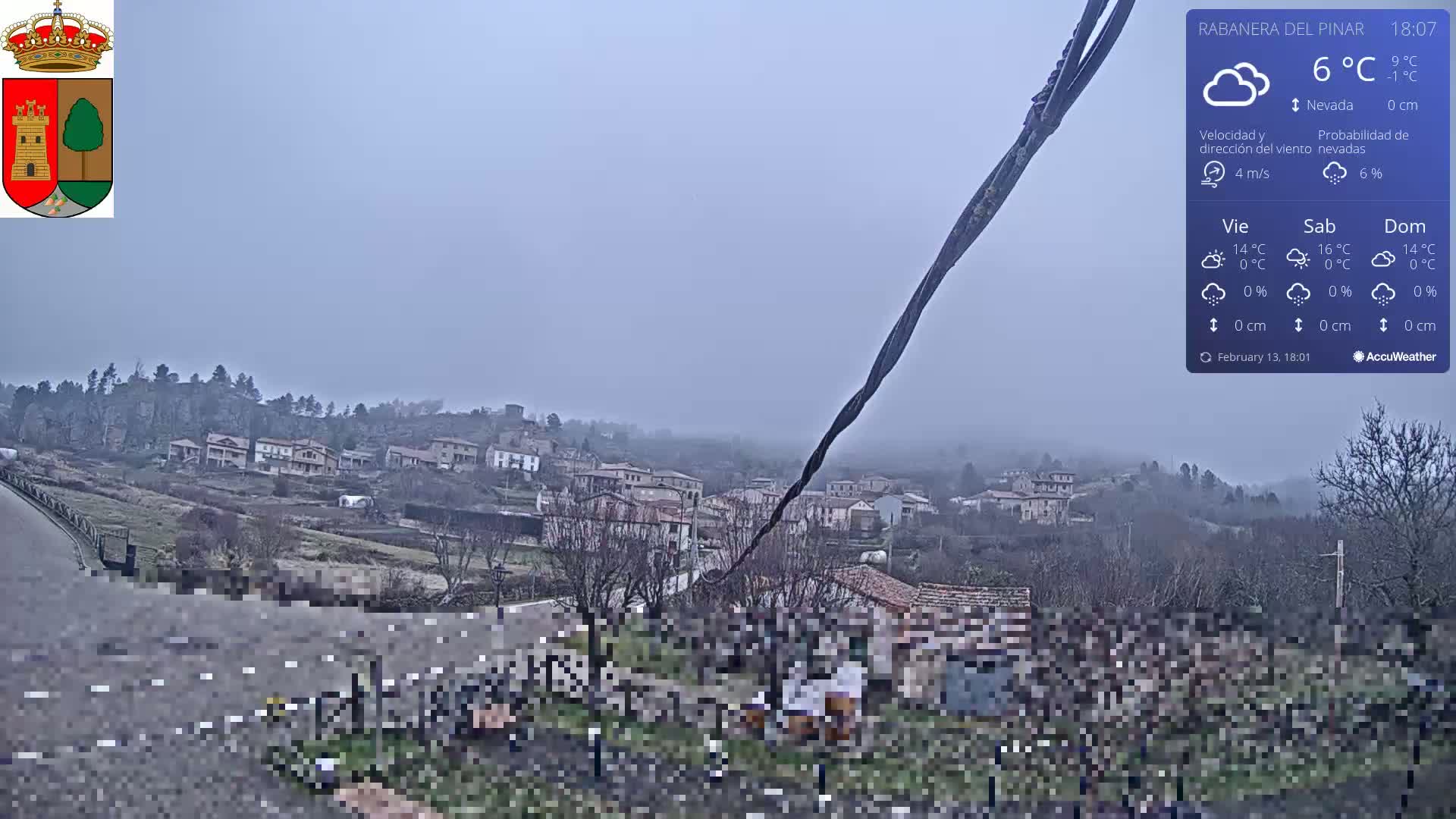 A hazy, lightly snowing village scene is visible from a roadside vantage point.