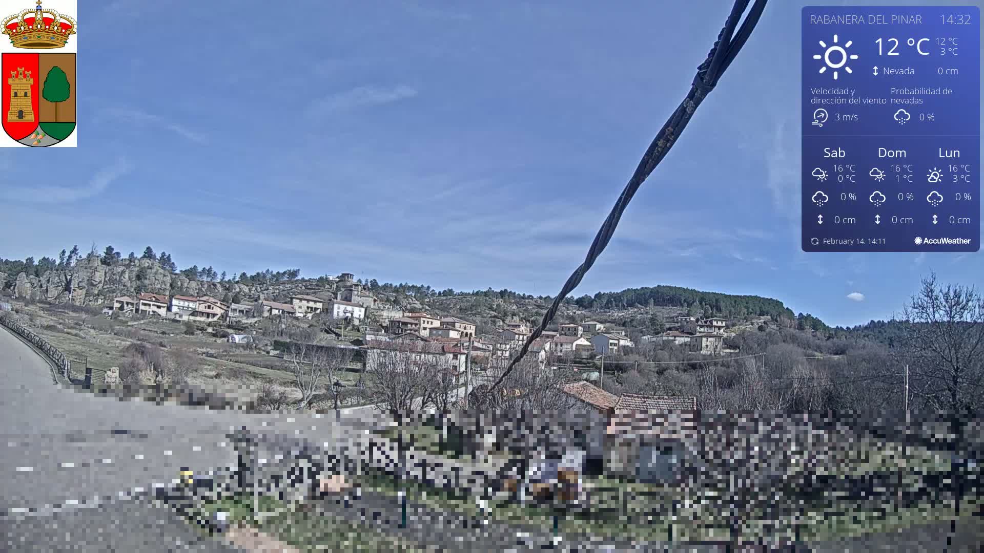 A small village nestled on a hillside under a clear blue sky, with a temperature of 12 degrees Celsius.