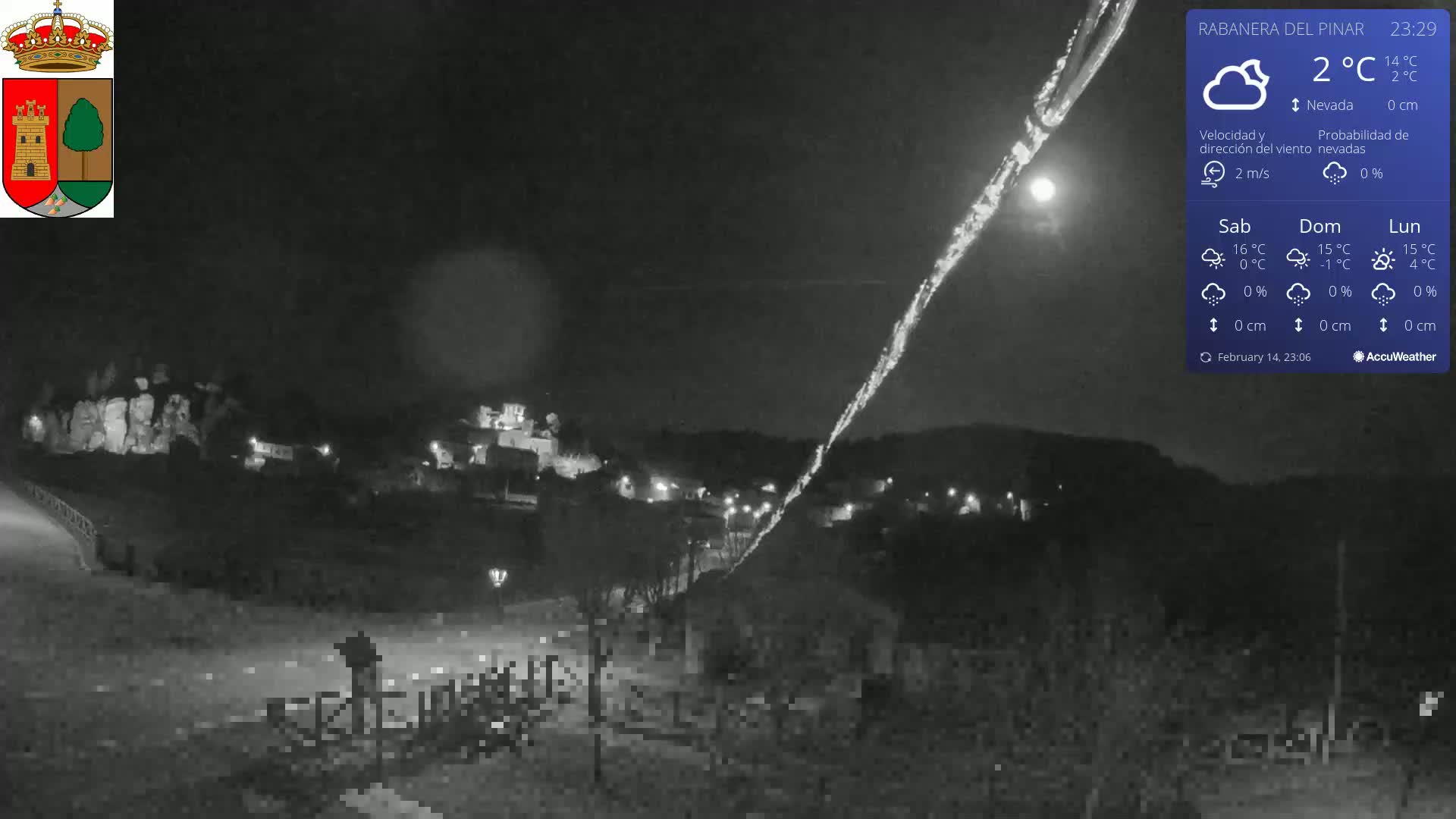 A nighttime, snowy scene shows a small town nestled in a valley under a mostly clear sky with a bright moon.