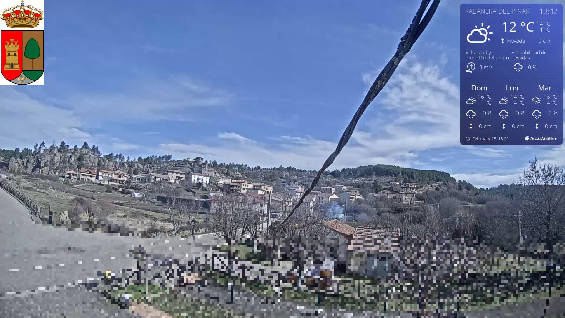 A mostly sunny view of a small town nestled in a hillside, with a few scattered clouds in the sky.
