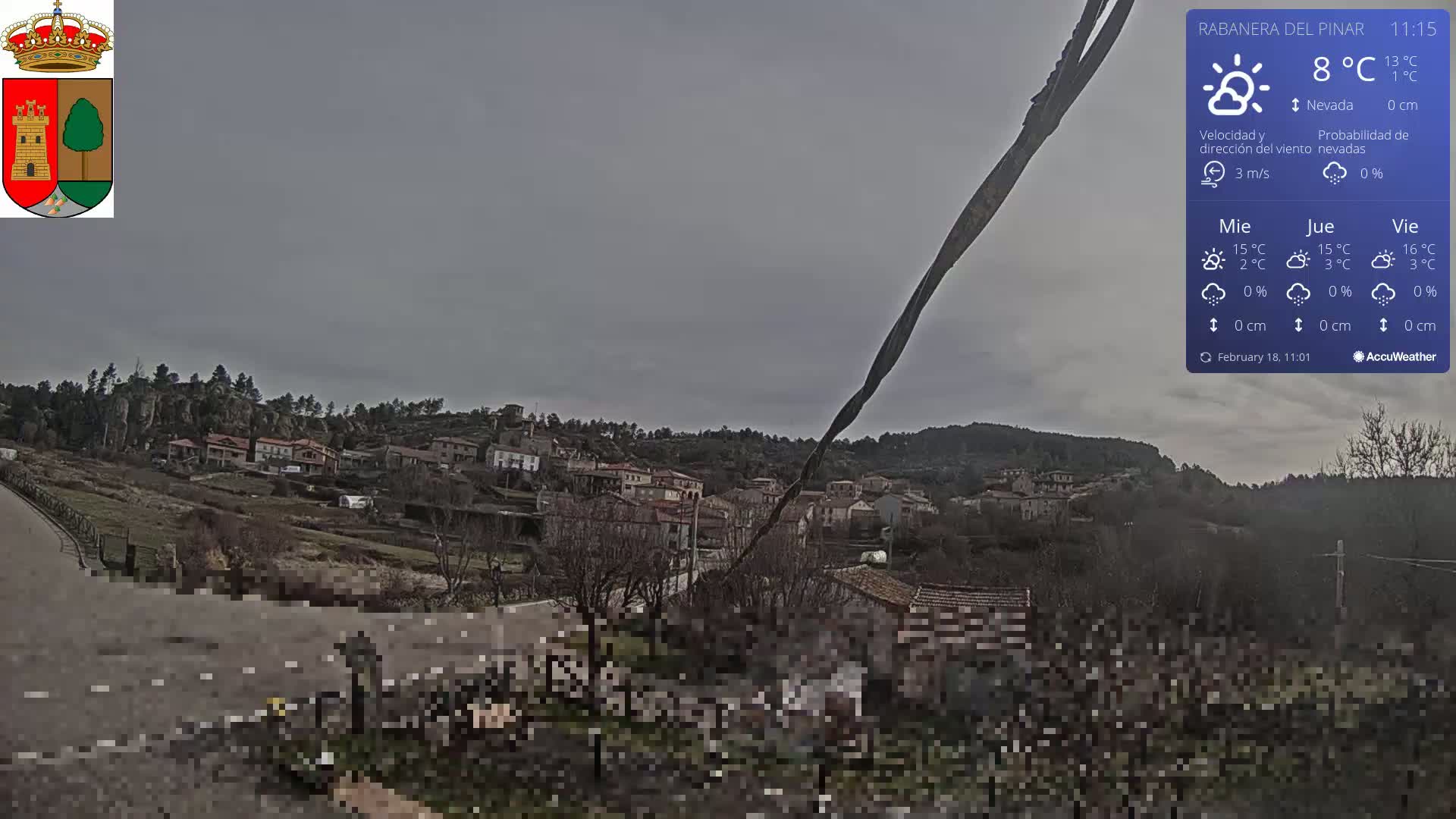 A small village nestled in a hillside, viewed from a slightly elevated position on an overcast day.