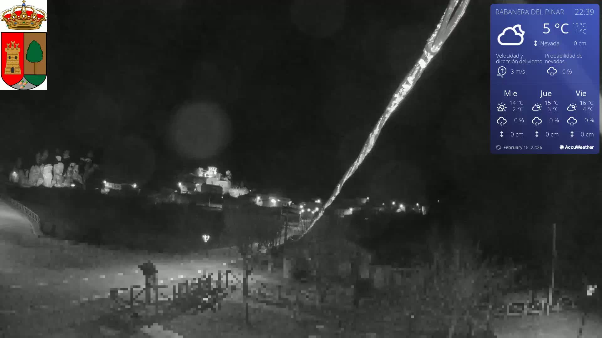 A nighttime view of a small town, illuminated sparsely, under a mostly clear sky with a 5°C temperature.