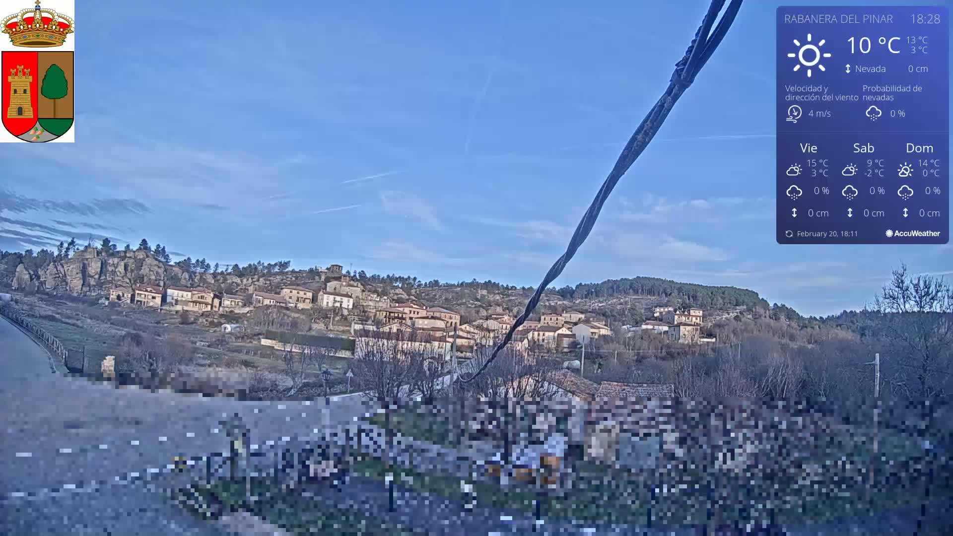 A small village nestled in a rocky hillside is visible under a clear blue sky.