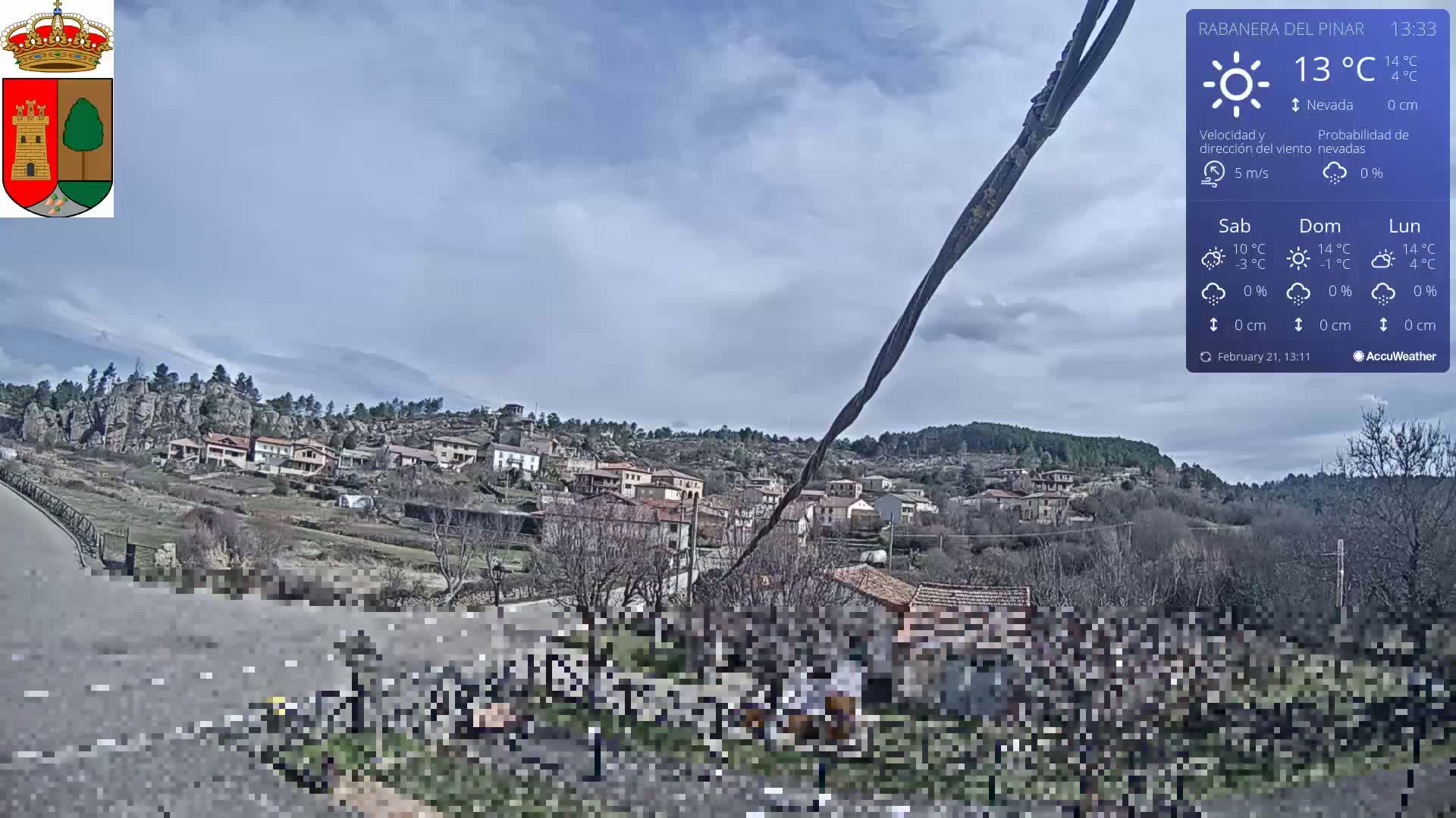 A small village nestled in a hillside, under a mostly cloudy sky, with a 5 m/s wind and a temperature of 13°C.