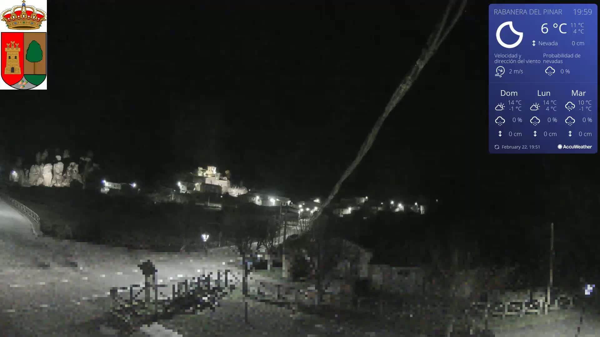 A nighttime, low-light view of a small town nestled in a dark landscape under a clear, cold sky.
