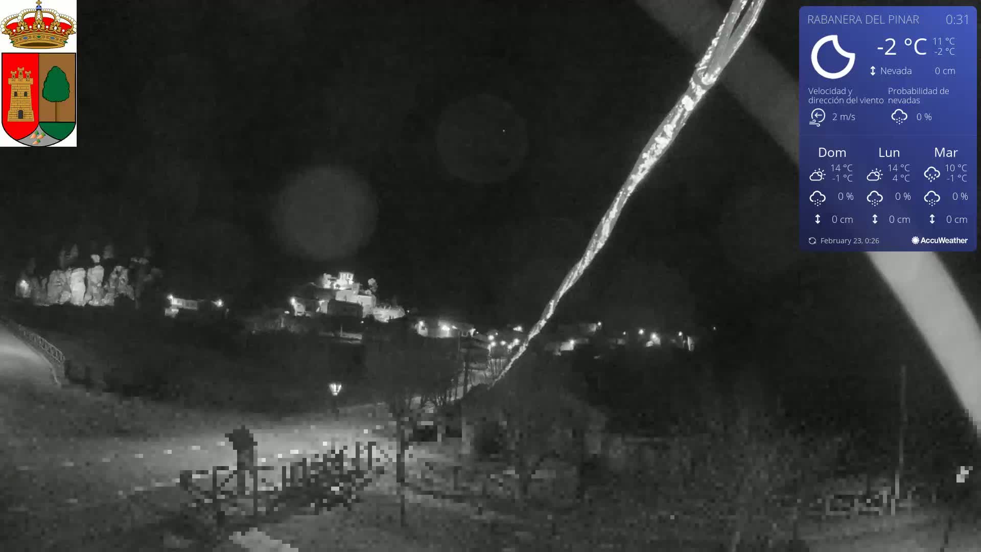 A nighttime view of a snow-covered town under a dark sky with a light dusting of snow.