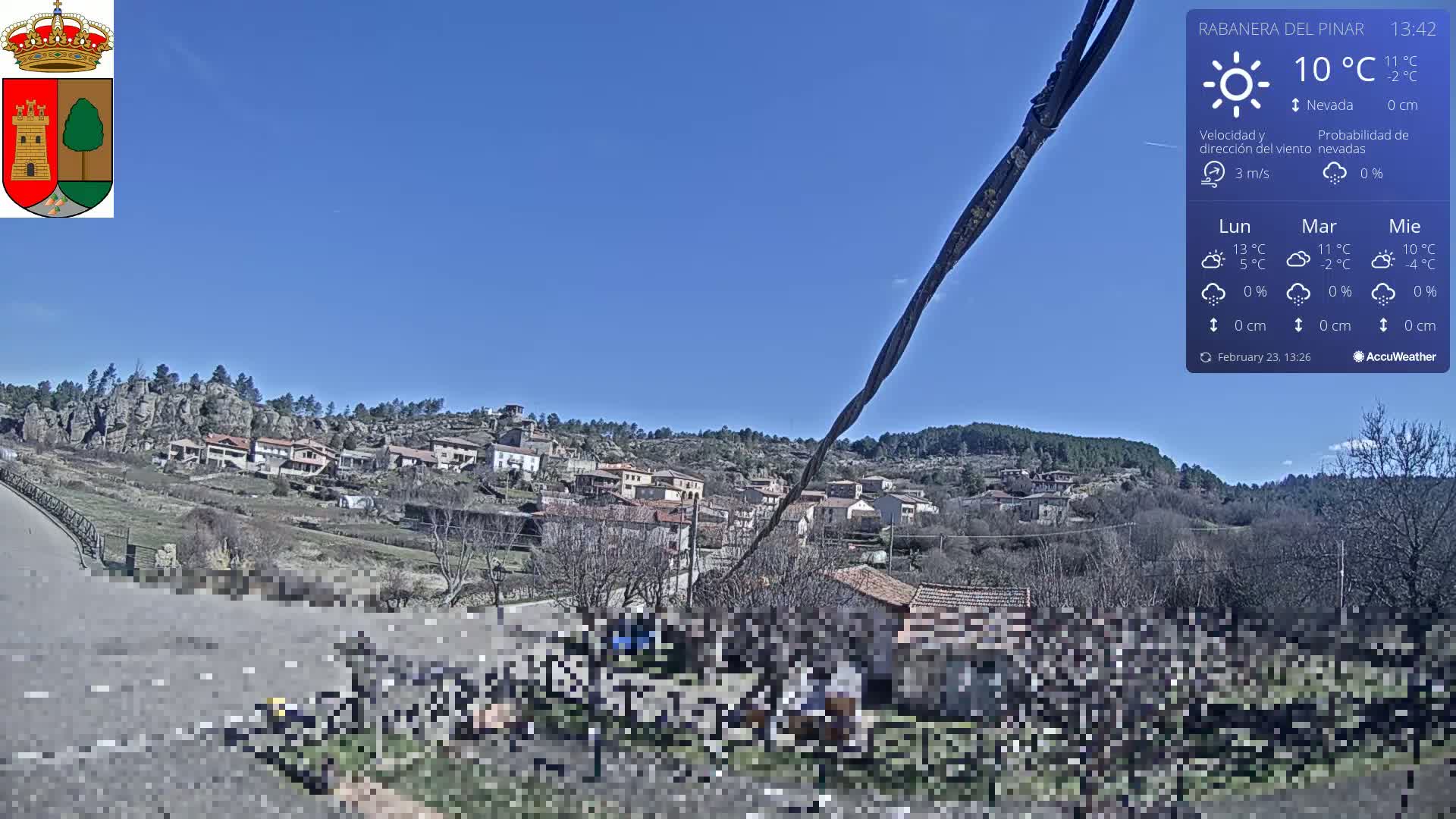 A small village nestled in a rocky hillside is visible under a clear blue sky.